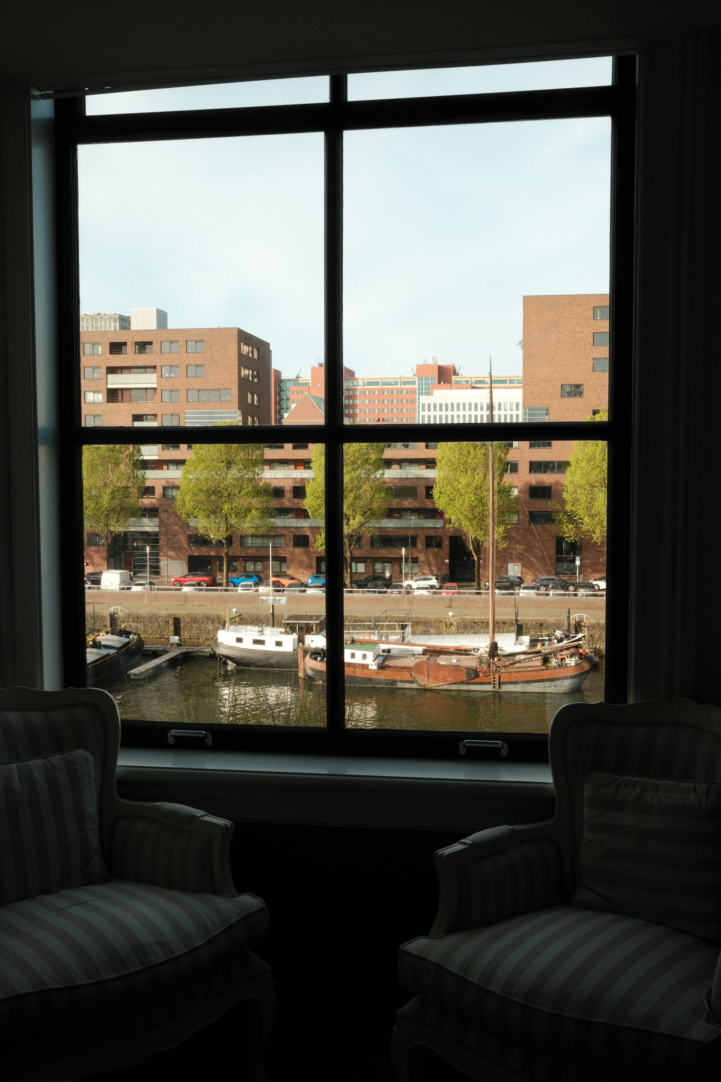 Canal view through large window with boats and Rotterdam skyline from Suite Hotel Pincoffs room