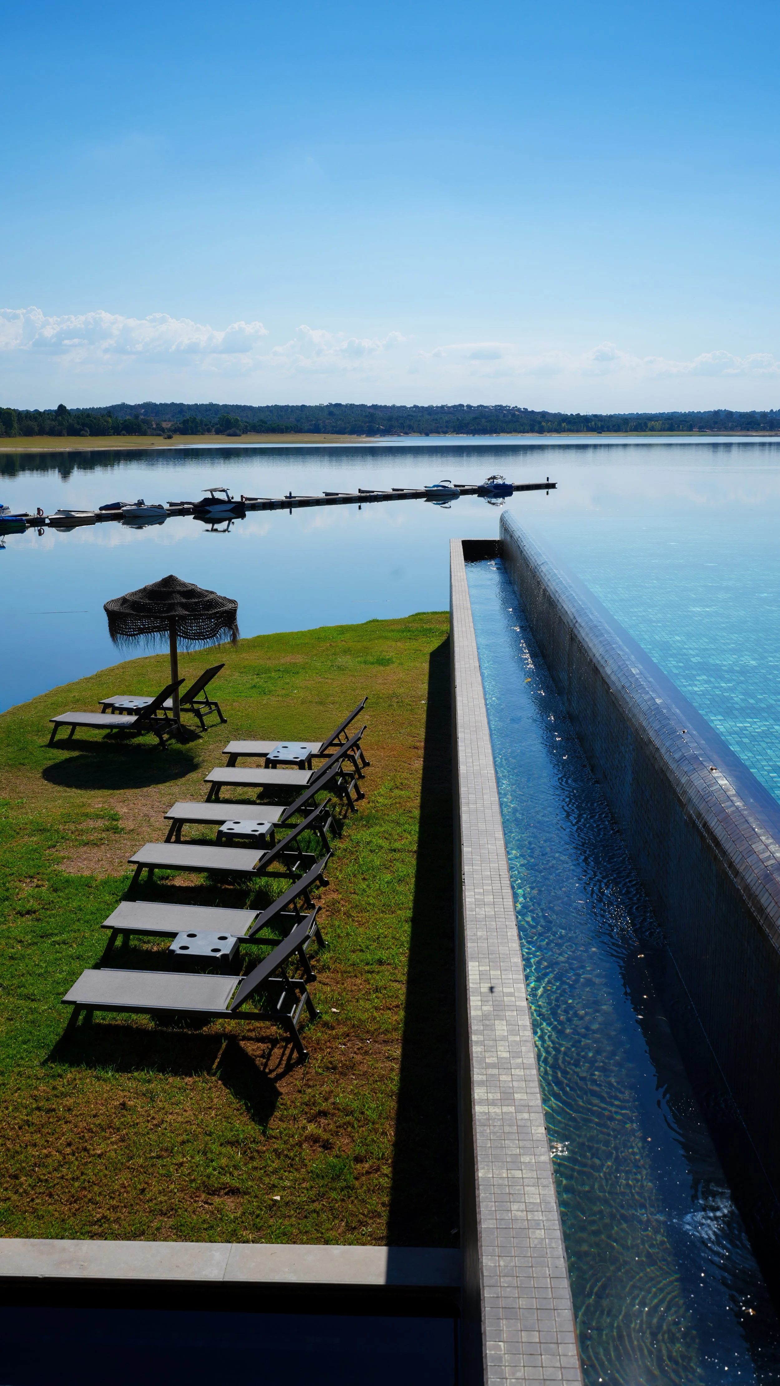 Infinity pool overlooking the peaceful Montargil reservoir with sun loungers and a lakeside relaxation area