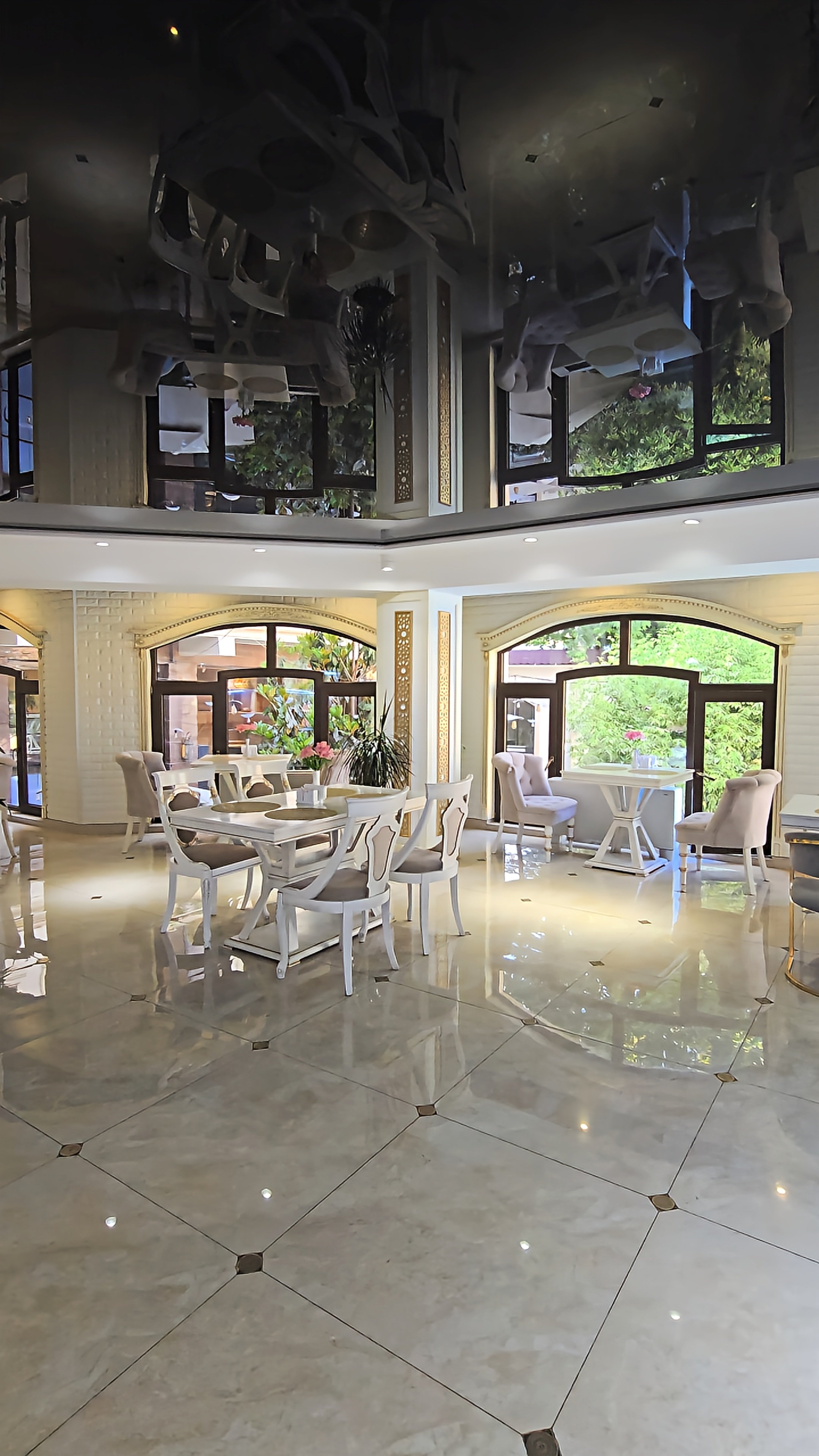 Elegant indoor restaurant with marble floors, mirrored ceiling and bright garden views at Dilimah Premium Luxury Hotel