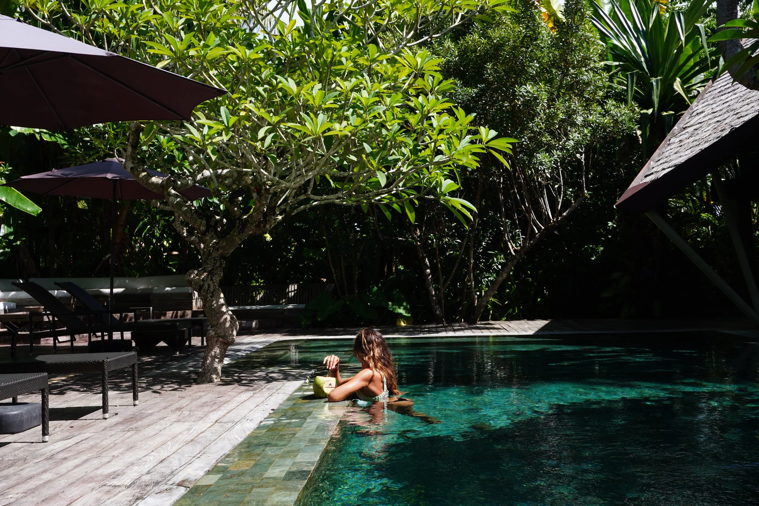 Guest enjoying the peaceful swimming pool beneath tropical trees and island sunshine