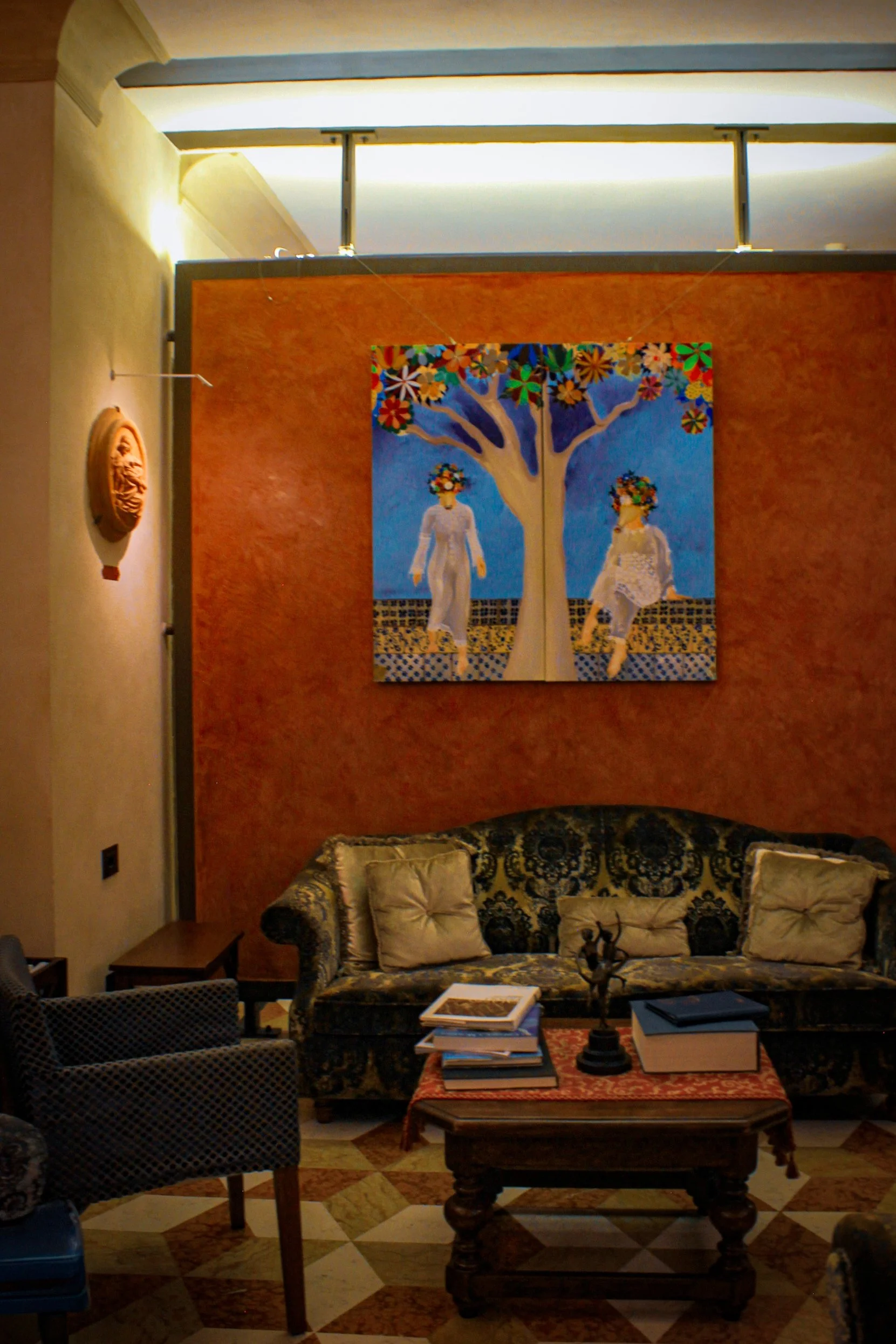 Cozy lounge with patterned sofa, contemporary artwork, and terracotta-toned walls, Art Hotel Commercianti – Bologna, Italy.