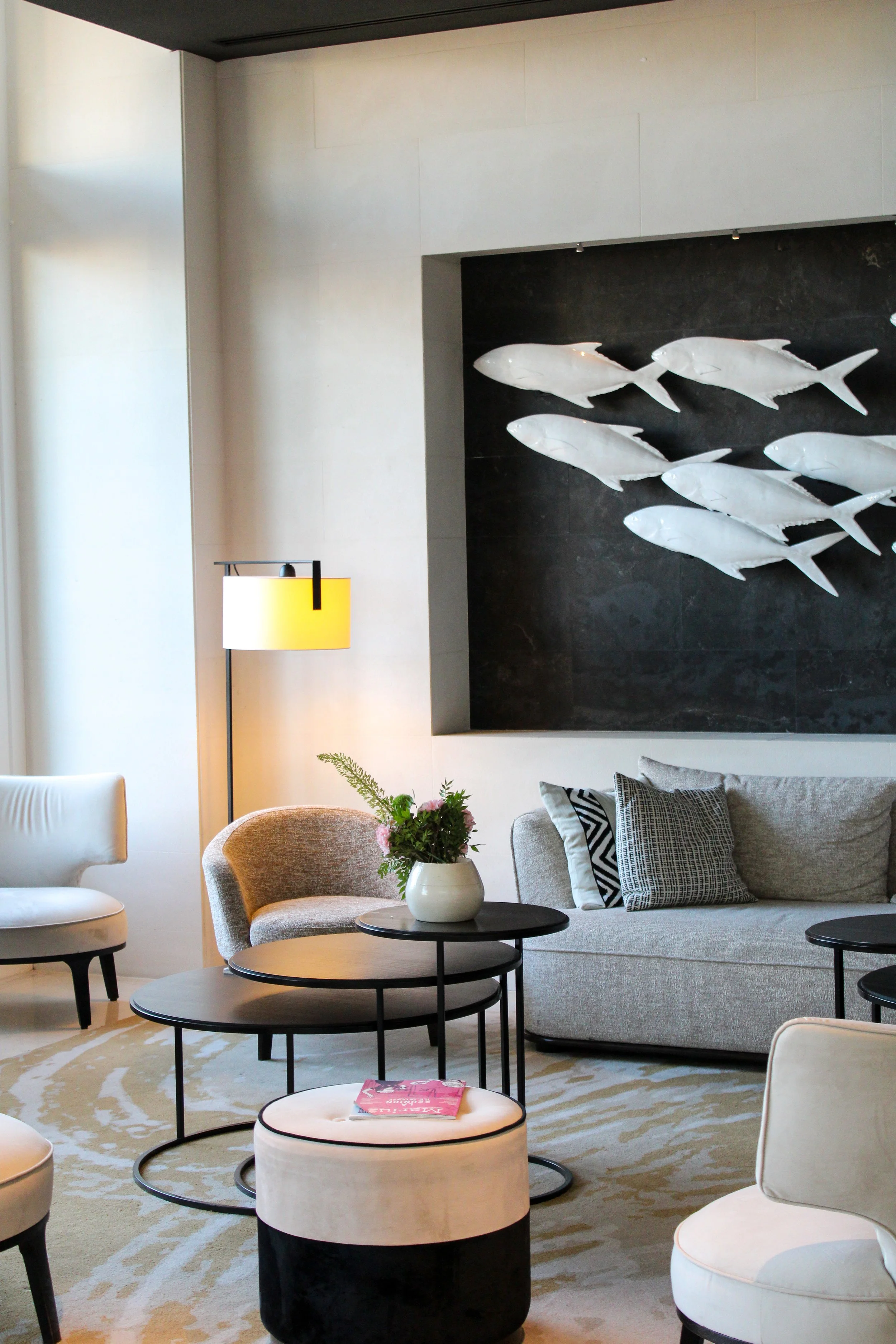 Elegant lounge featuring modern furnishings and artistic fish wall installation