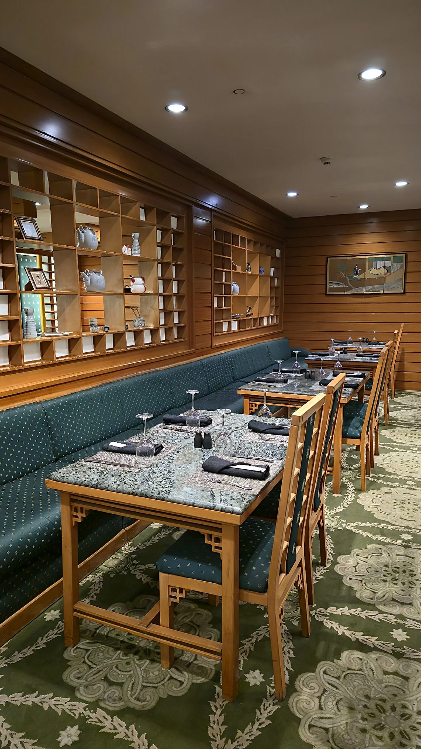 Intimate dining room with wooden shelving, green upholstery, and neatly set tables for a refined culinary experience, Sonesta St. George Hotel Luxor.