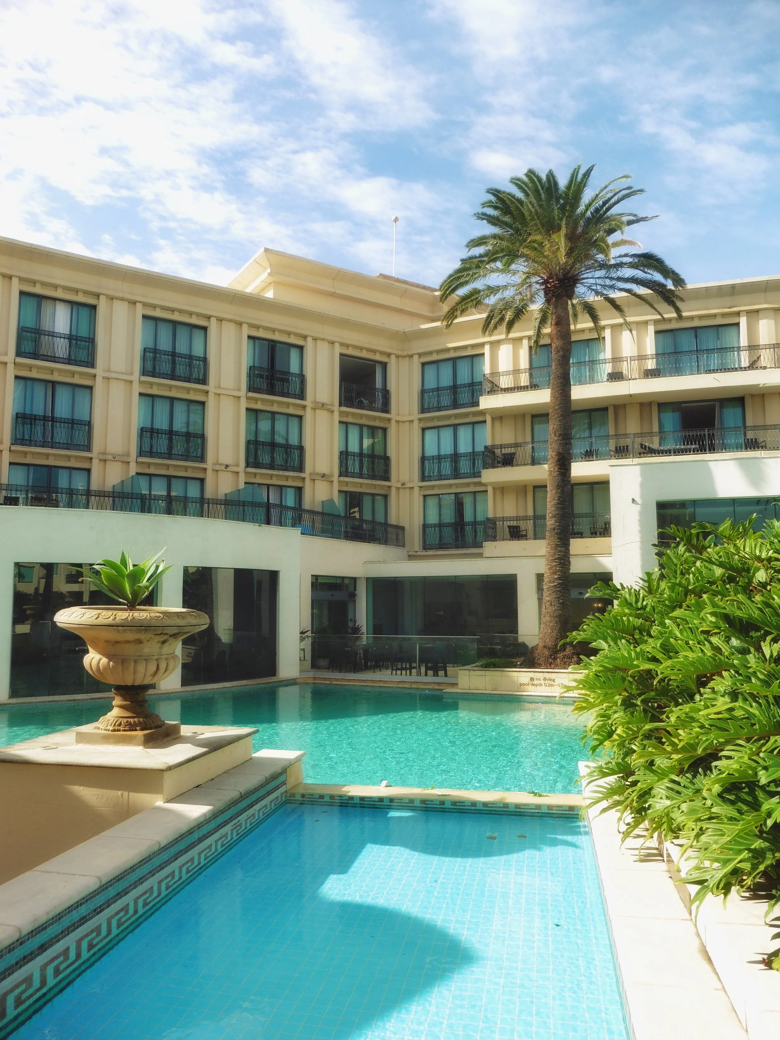 Palm-lined courtyard pool surrounded by elegant resort architecture at Imperial Hotel Gold Coast