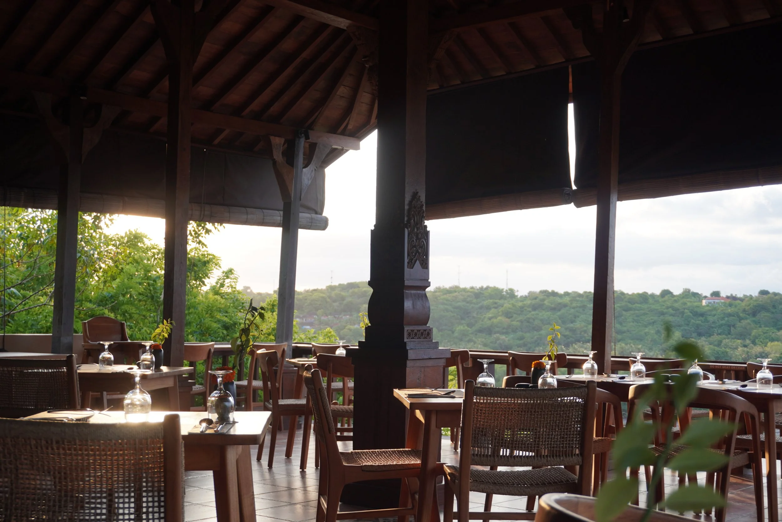 Open-air restaurant overlooking tropical landscapes at sunset