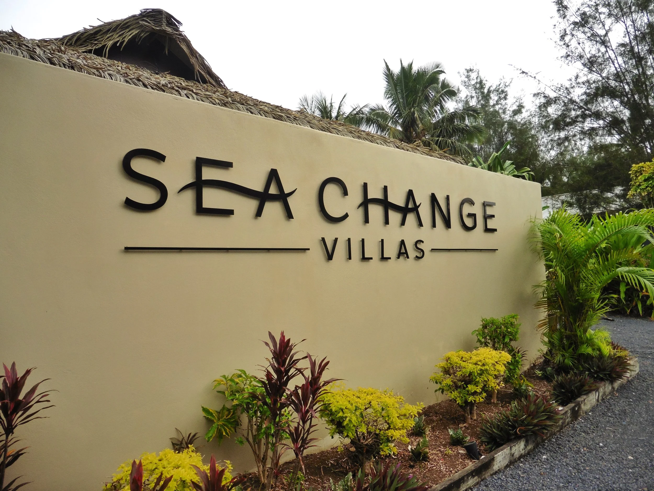 Entrance sign surrounded by lush tropical greenery at Sea Change Villas, Rarotonga, Cook Islands
