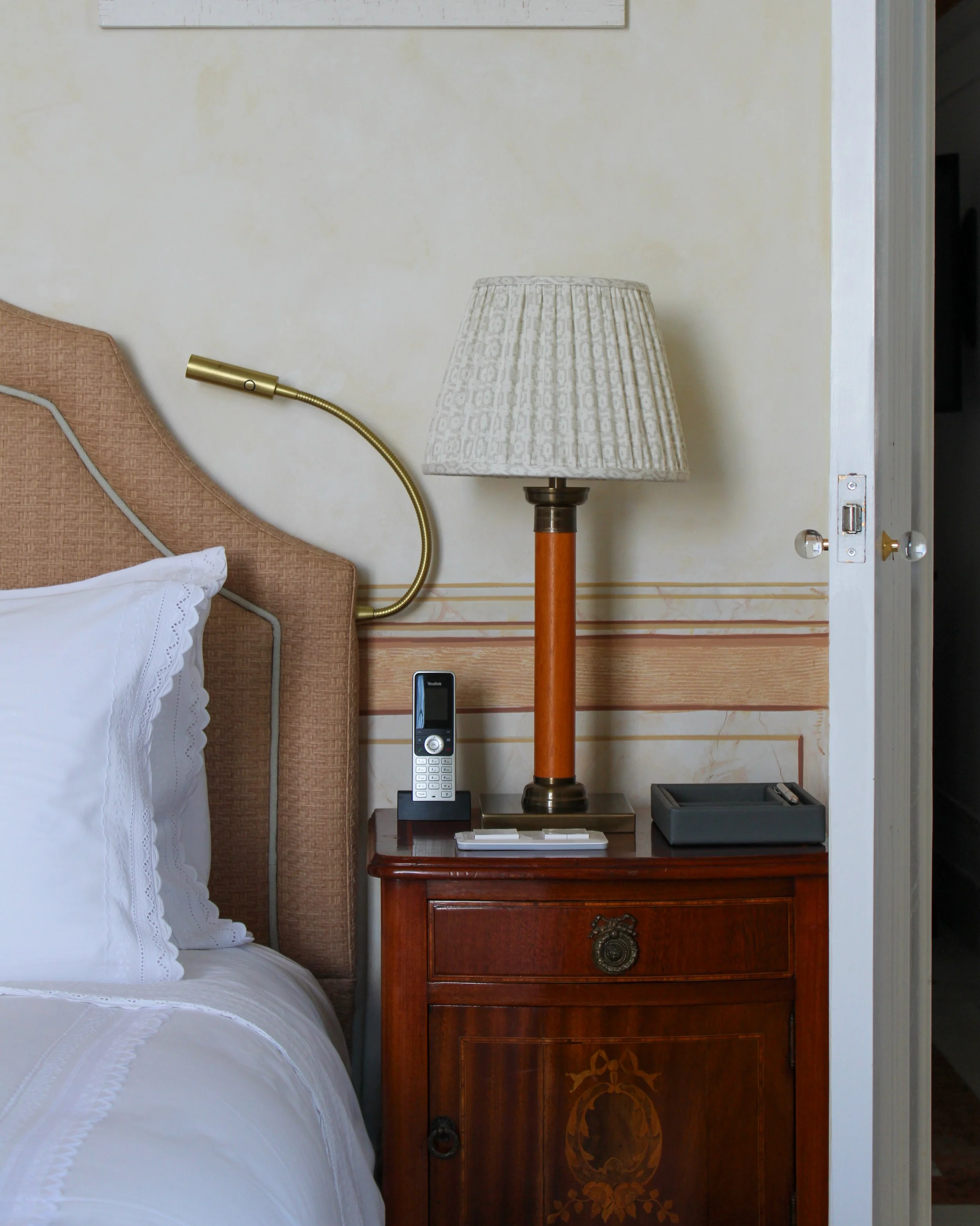 Classic bedside vignette with vintage lamp, warm wood tones, and curated details in a serene guest room, Estoril Vintage Hotel – Estoril, Portugal.