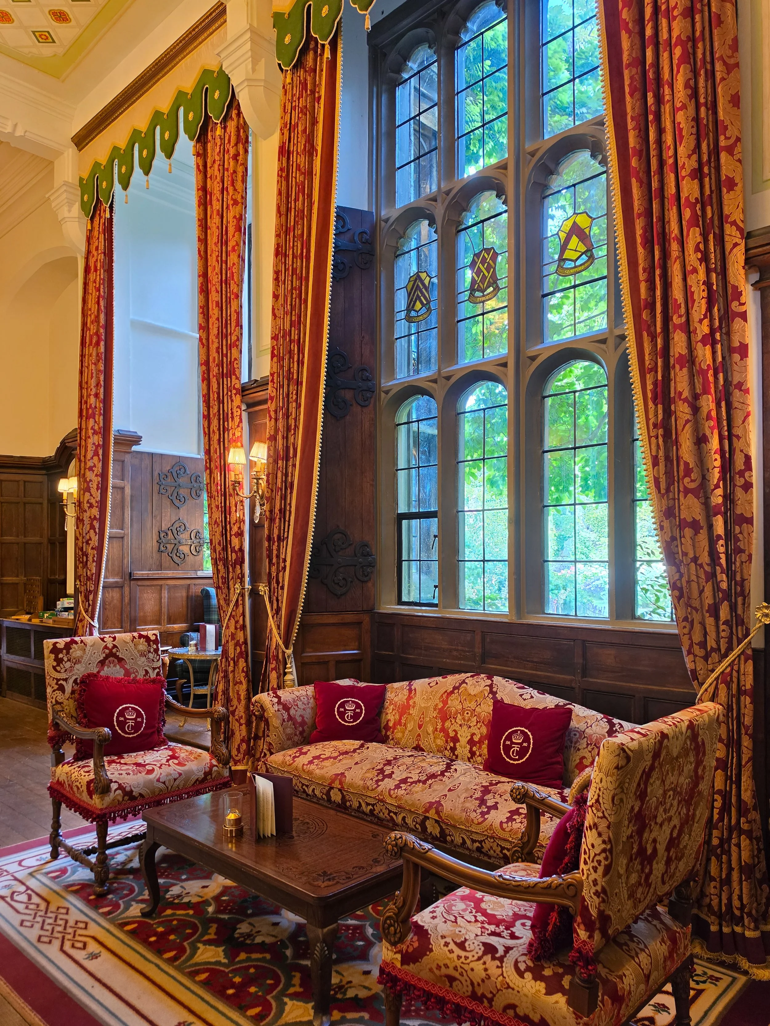 Historic Tudor lounge with stained glass windows, antique furnishings, and elegant castle interiors