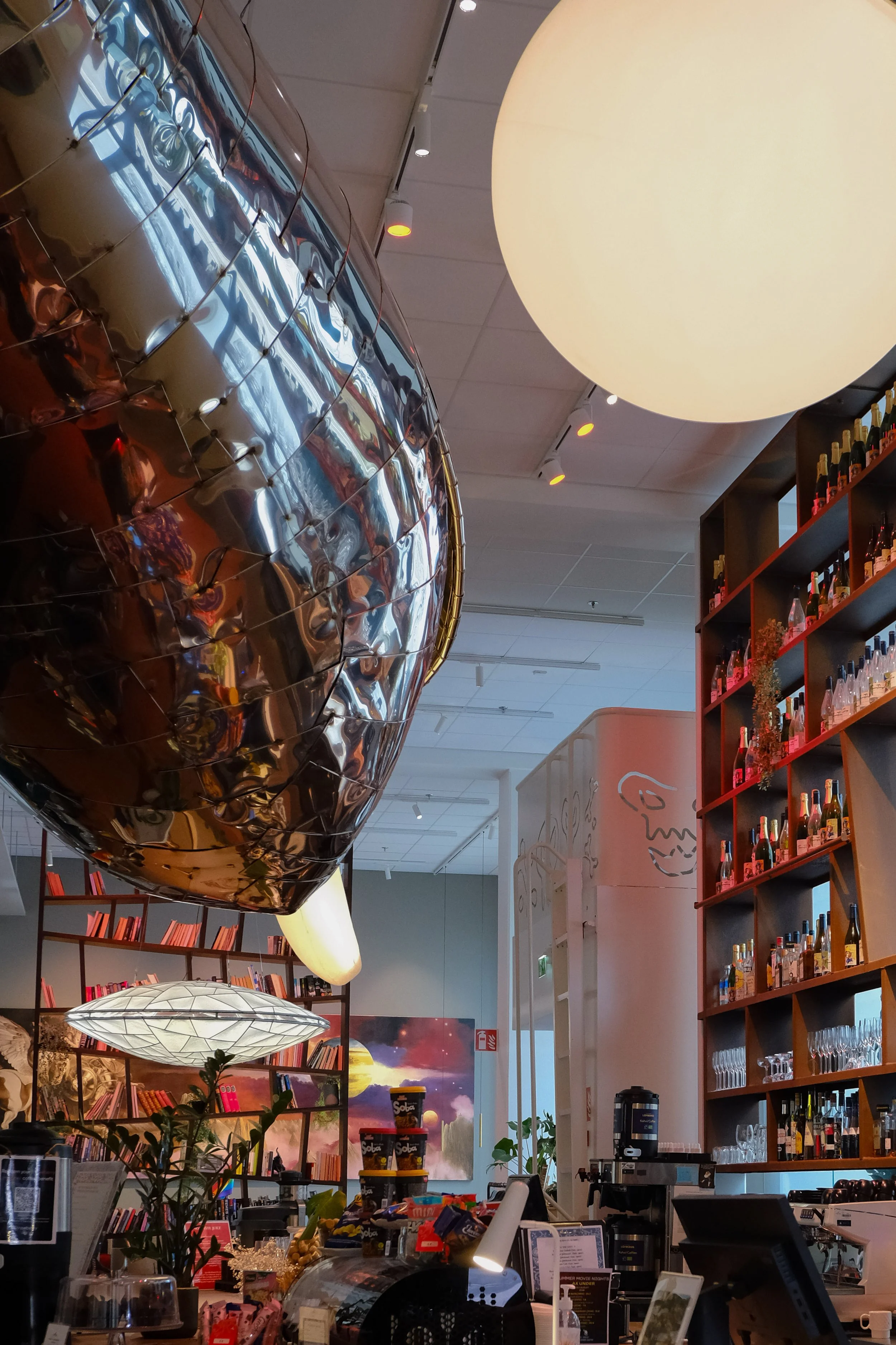 Contemporary lobby featuring suspended artwork, bookshelves, and social spaces