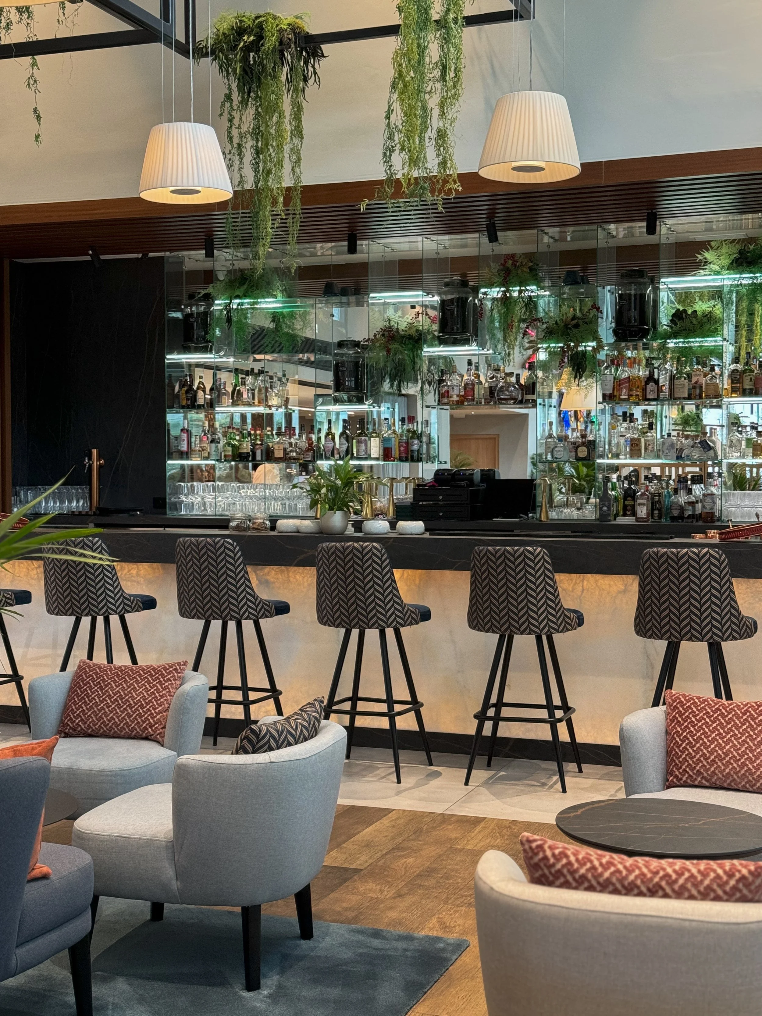 Elegant lobby bar with botanical design, premium spirits, and relaxed lounge seating