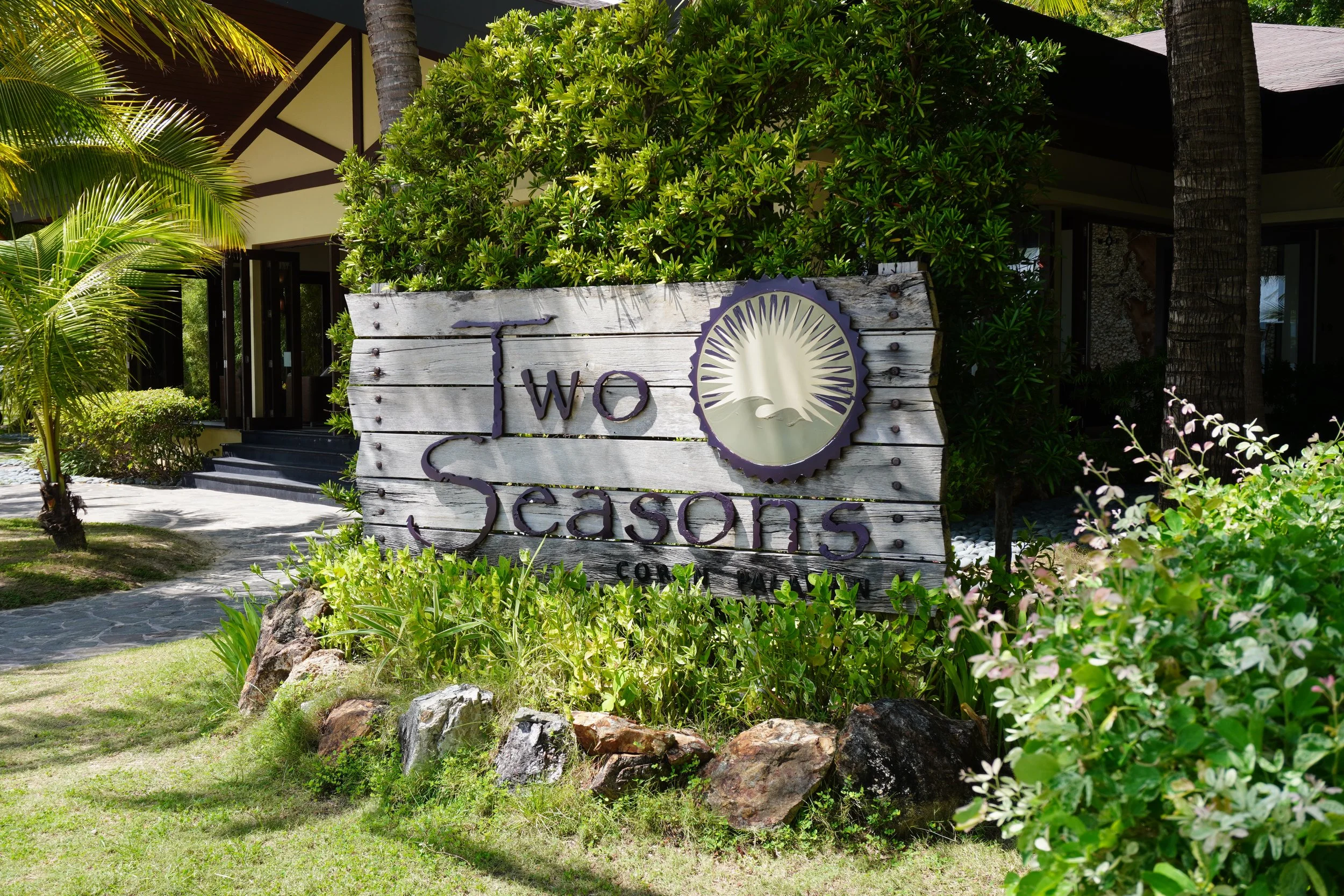 Beachfront resort entrance surrounded by tropical gardens and lush greenery
