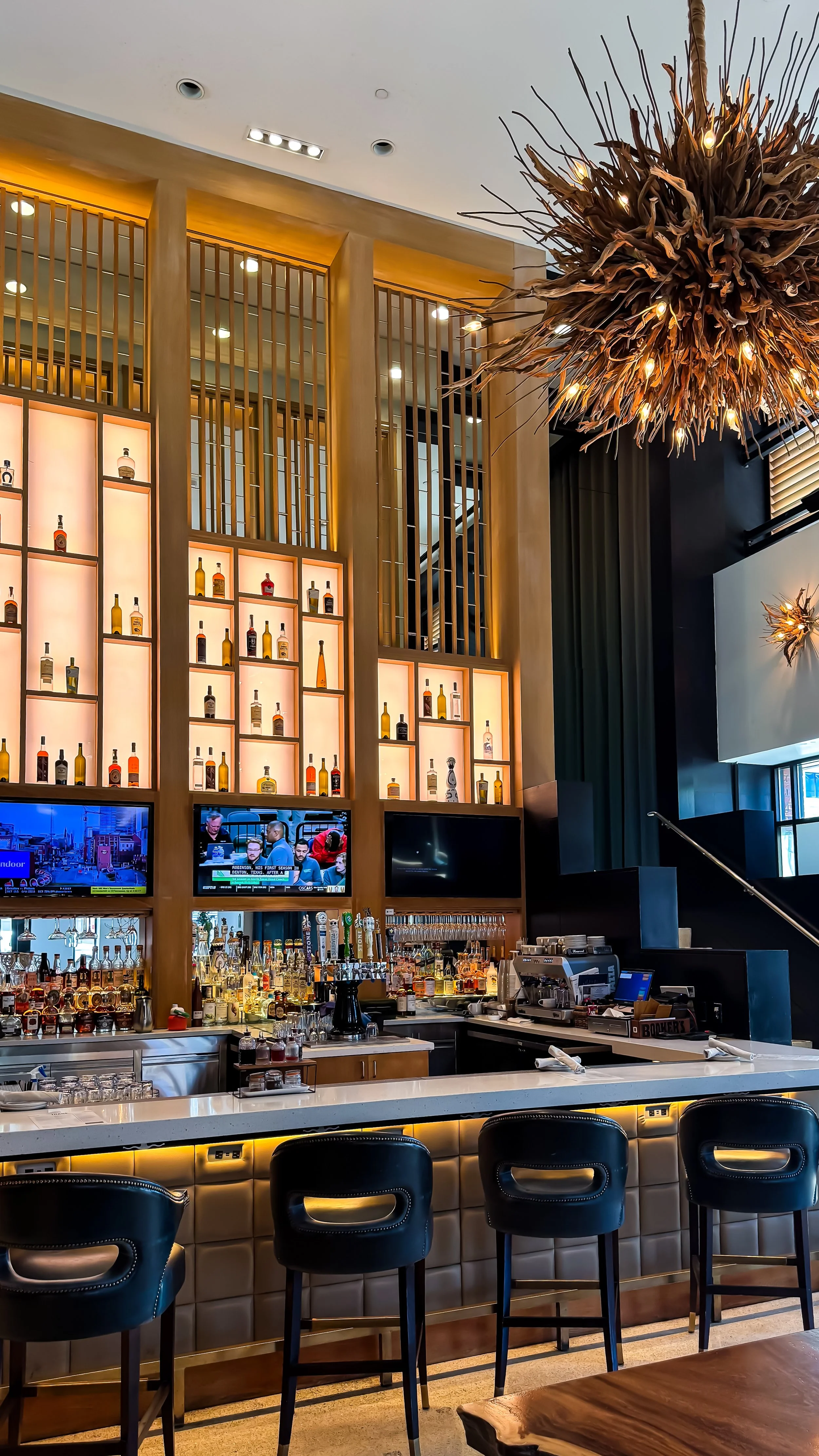 Sophisticated lobby bar featuring illuminated spirits display, handcrafted cocktails, and contemporary interiors