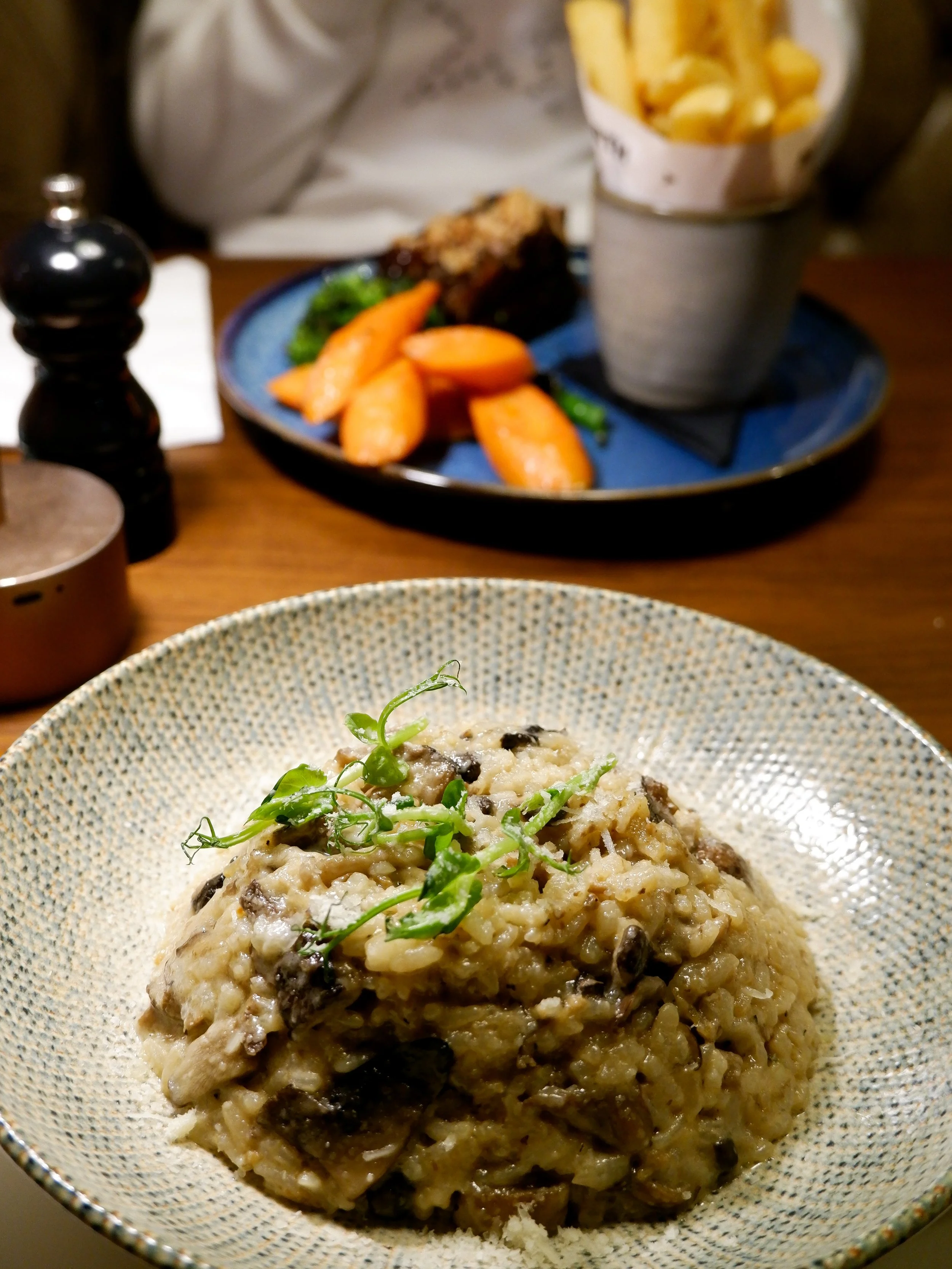 Creamy mushroom risotto garnished with fresh herbs and served in a textured ceramic bowl