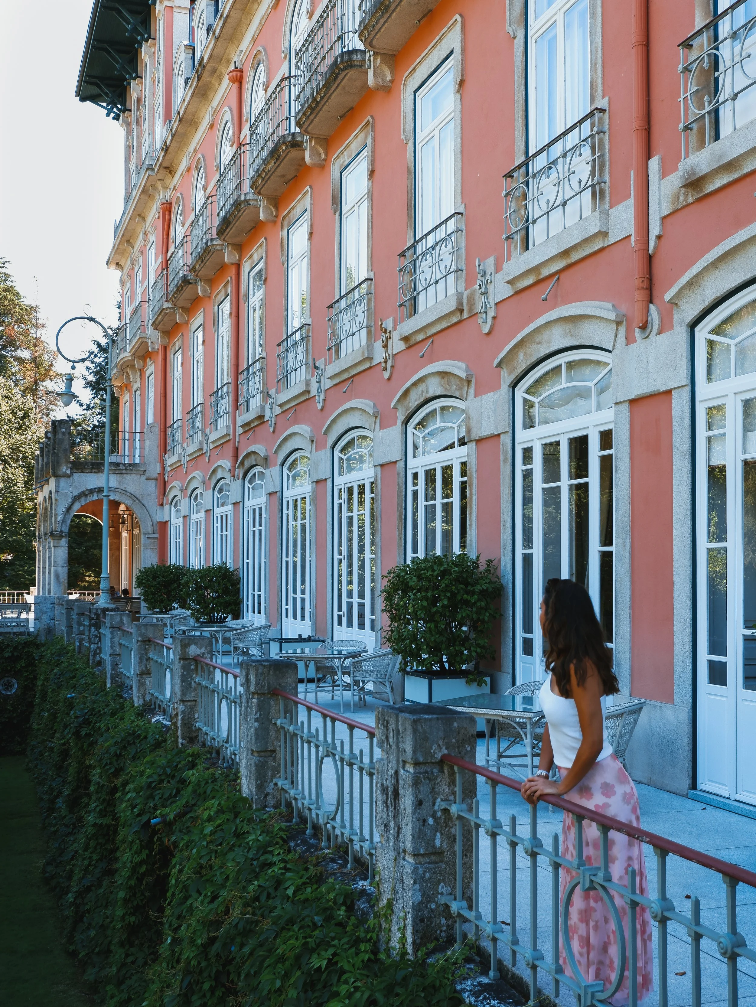 Elegant palace hotel façade with private balconies overlooking landscaped gardens and historic architecture