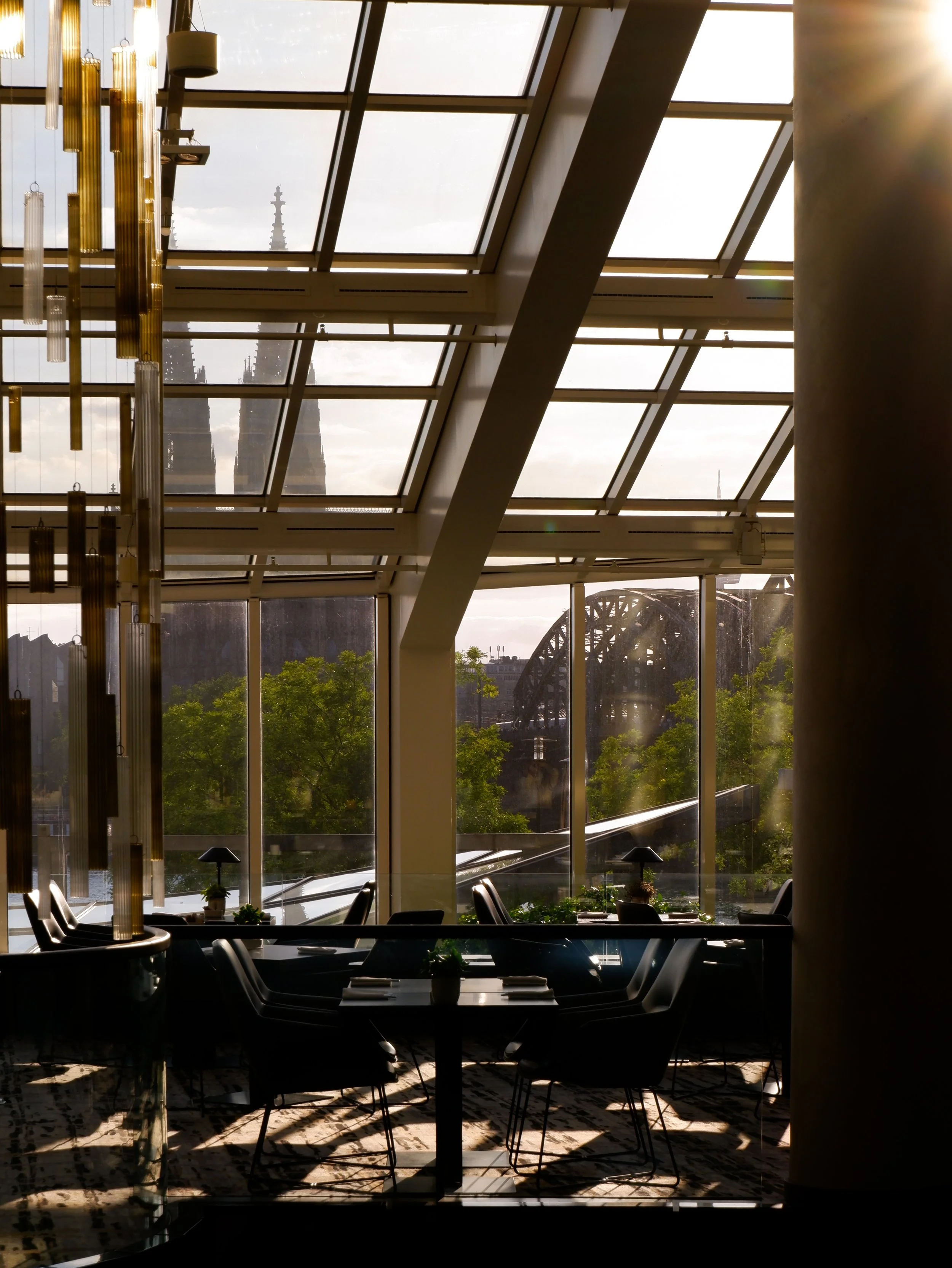 Light-filled lounge with floor-to-ceiling windows overlooking Cologne Cathedral and the Rhine River