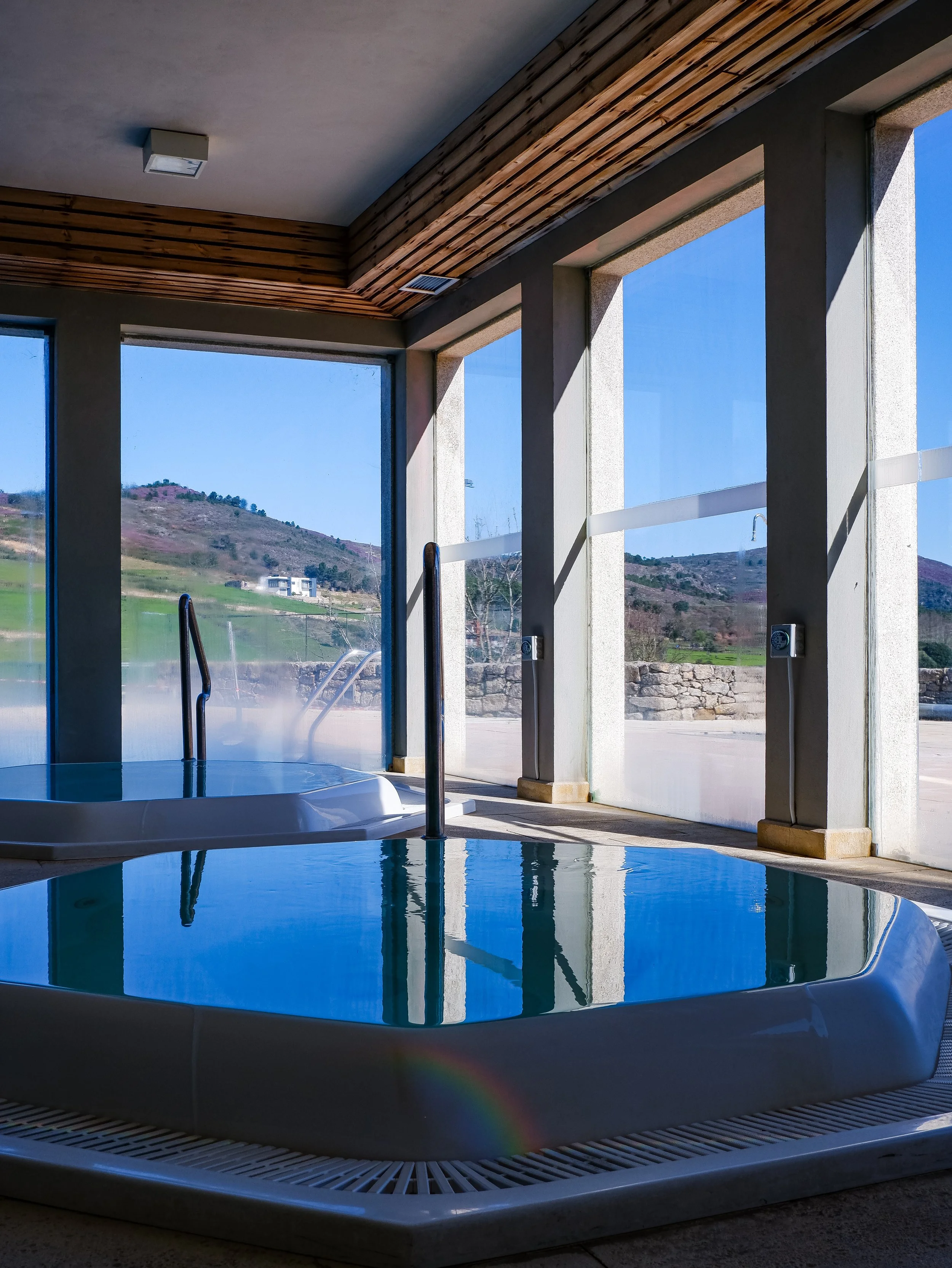 Indoor spa pool with natural light and countryside views through large windows, offering a tranquil wellness experience, Casas Novas Countryside Hotel Spa & Events – Chaves, Portugal.
