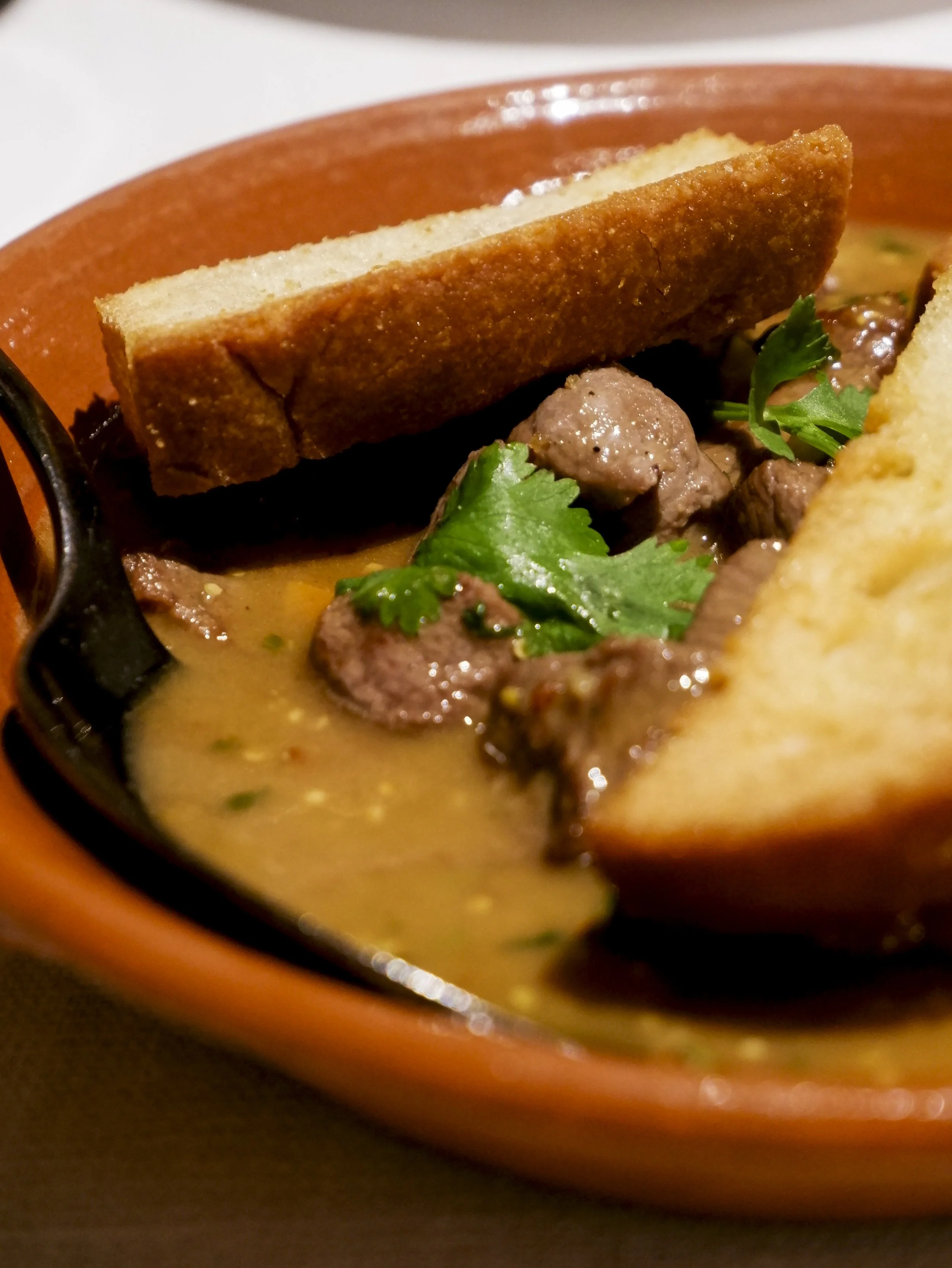 Close-up of a traditional Alentejo stew served with rustic bread and fresh herbs — Octant Évora
