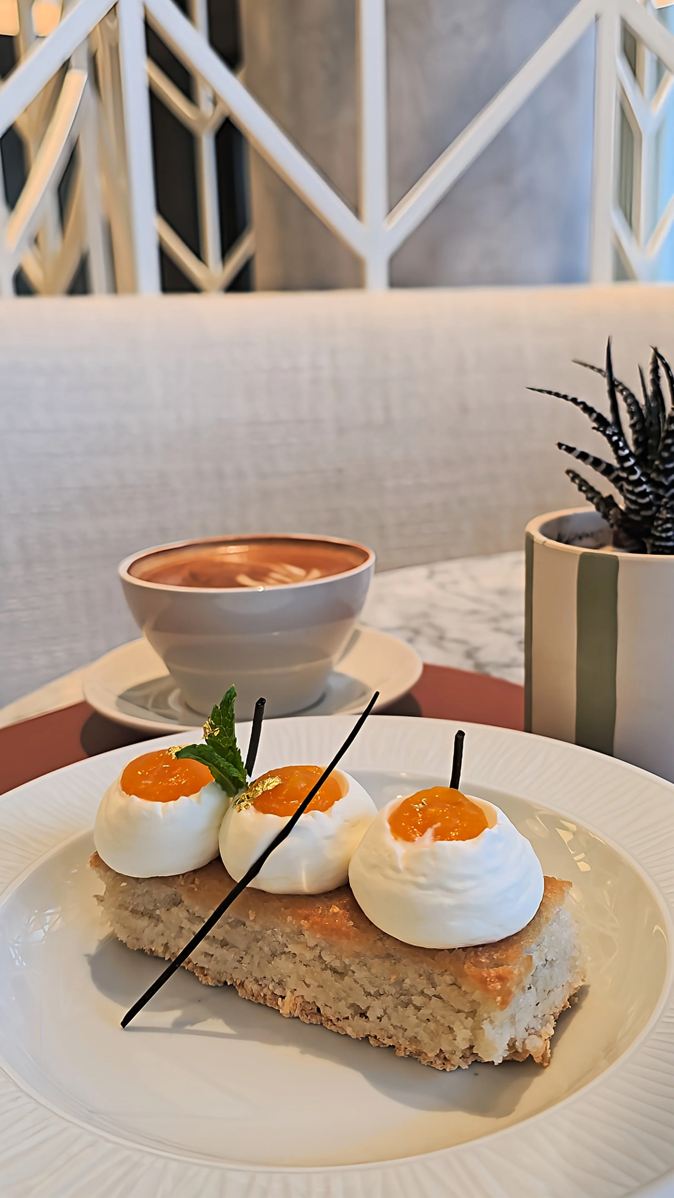 Gourmet dessert featuring delicate cream domes, orange fruit topping, fresh mint, and a cup of coffee