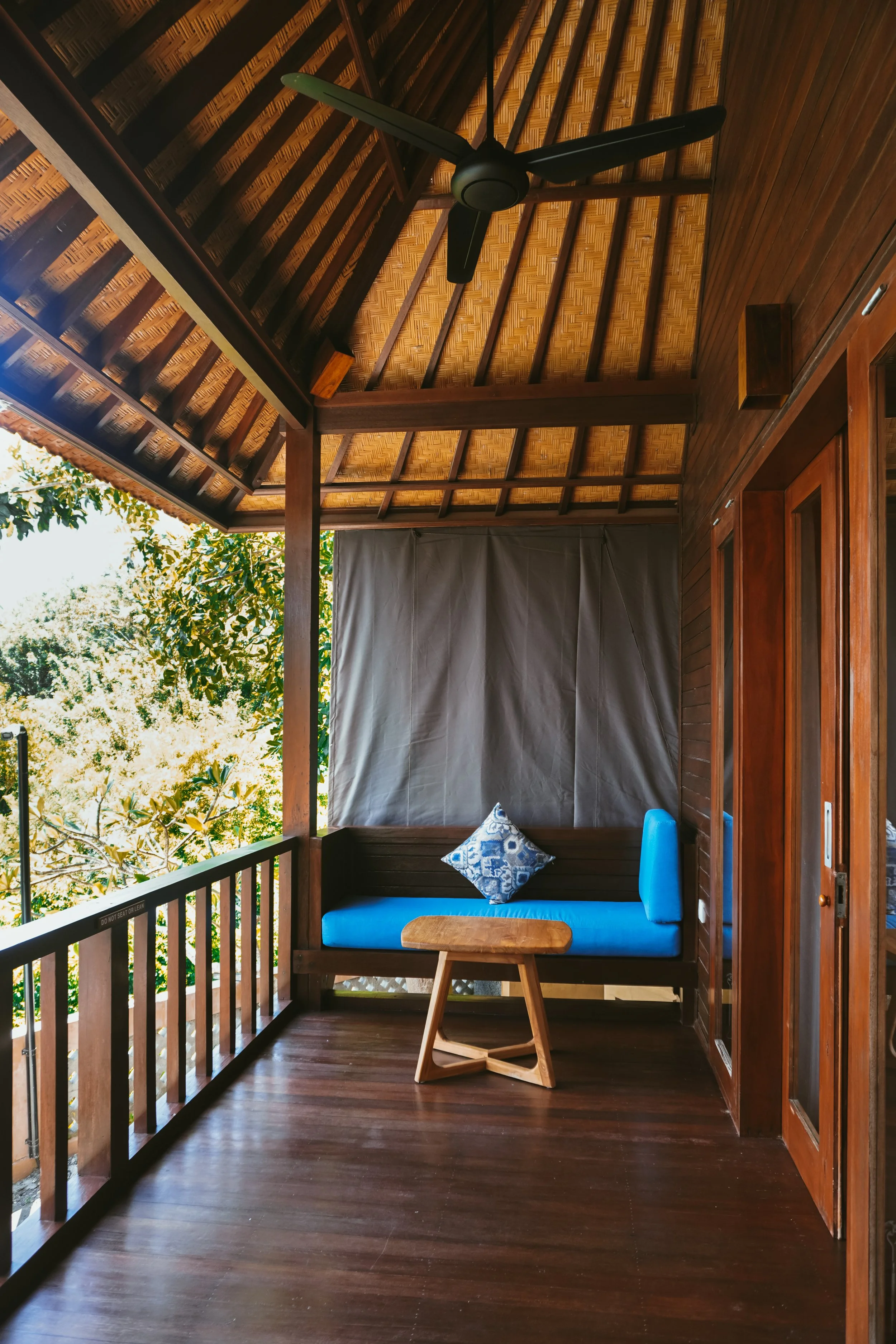 Private wooden balcony with lounge seating and tropical jungle views at Pramana Nusa Ceningan Resort Bali