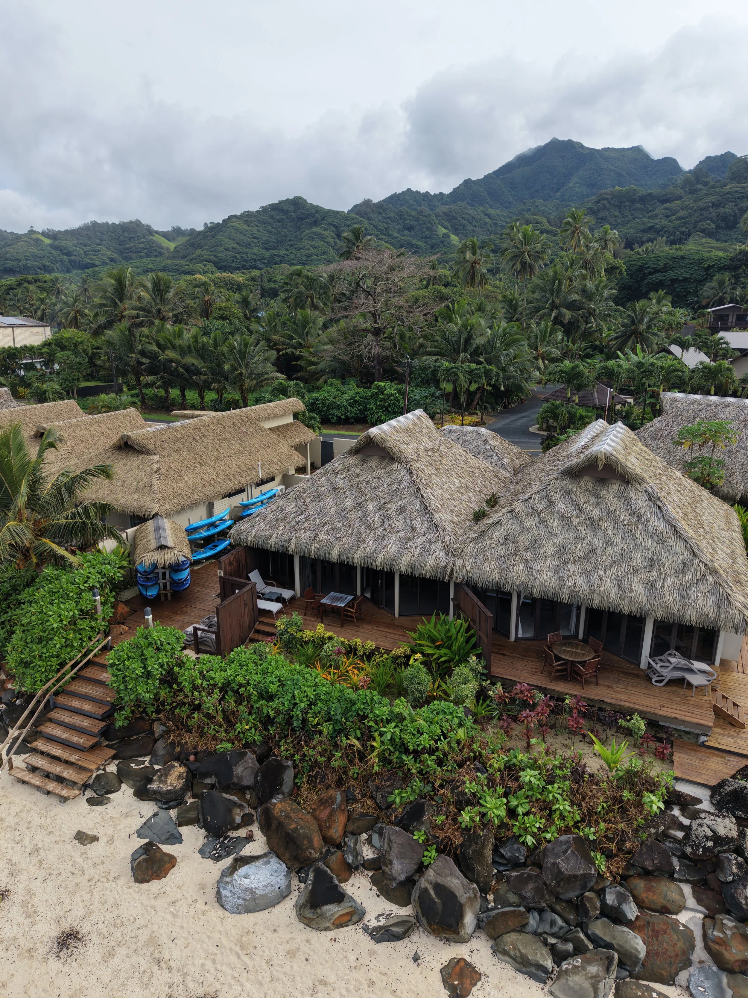 Beachfront villas surrounded by tropical mountains and palm trees at Sea Change Villas in Rarotonga, Cook Islands