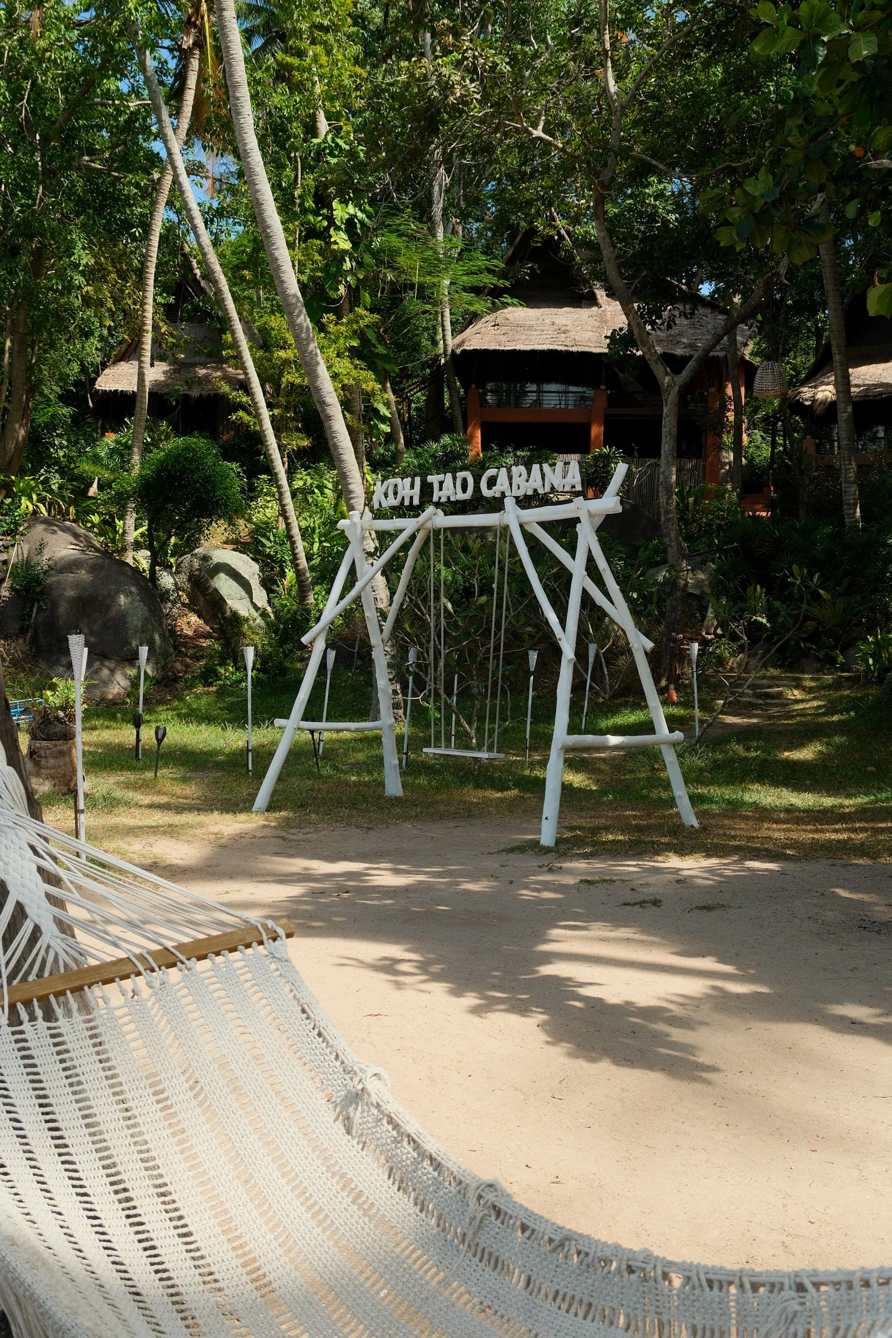 Hammock and garden swing tucked among palms and lush tropical vegetation