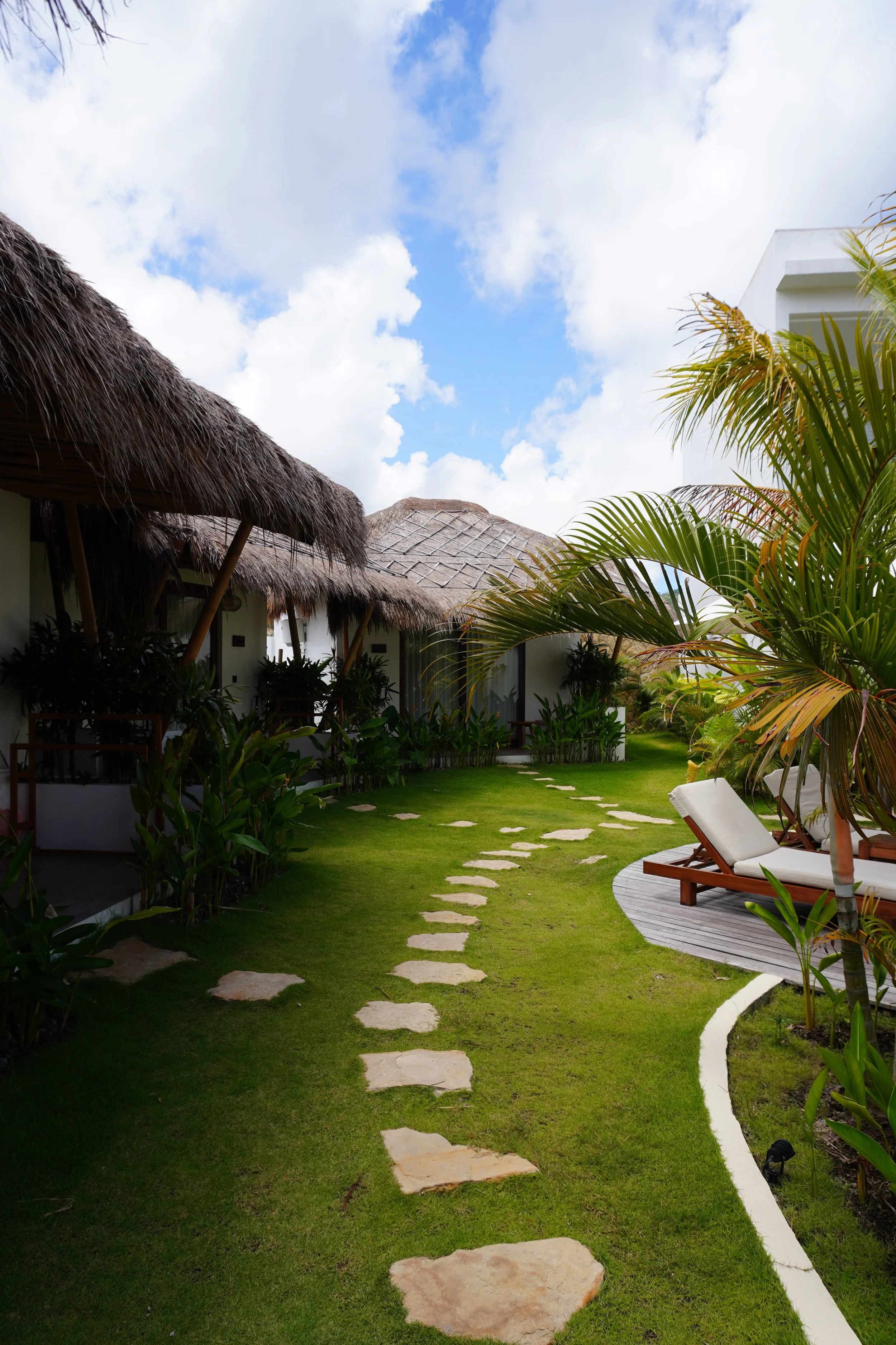 Garden pathway leading through tropical landscapes and stylish guest villas