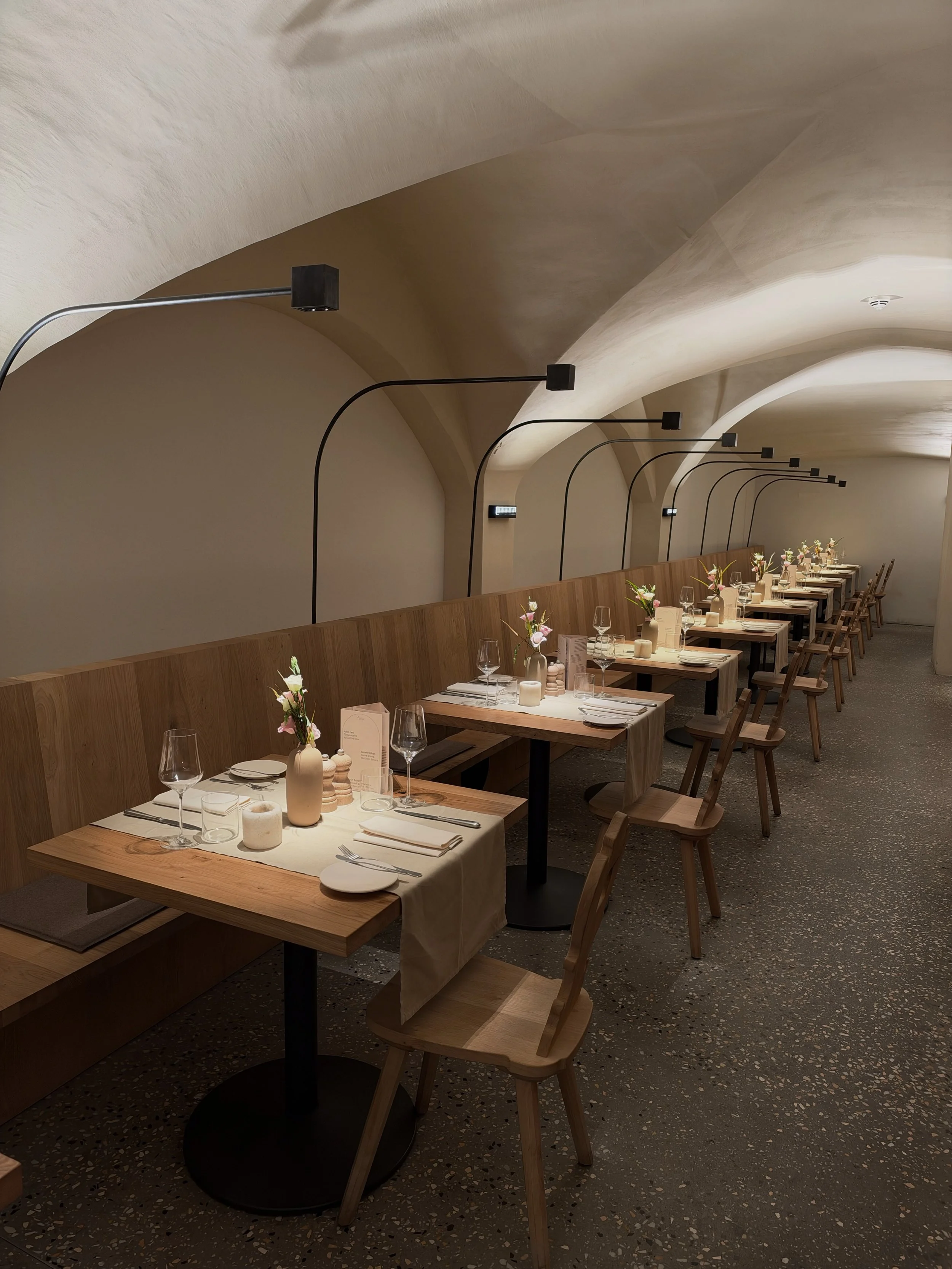 Contemporary restaurant interior with vaulted ceilings, wooden furniture, and elegantly arranged dining tables