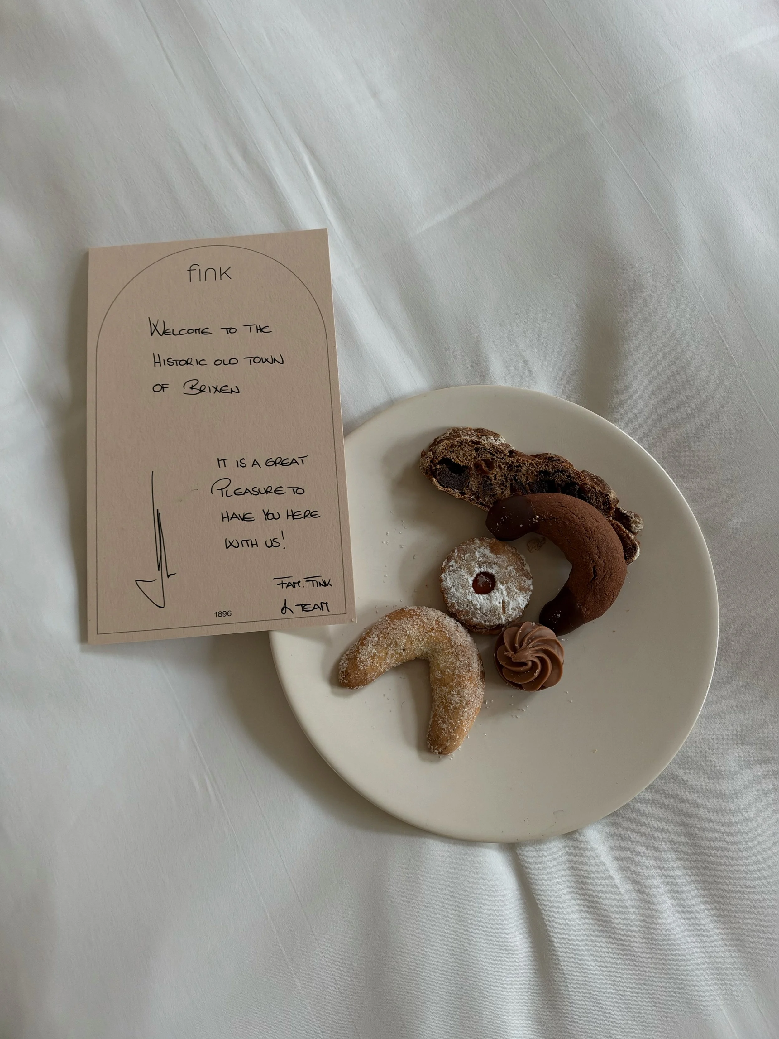 Selection of homemade welcome pastries presented on a ceramic plate beside a handwritten greeting card