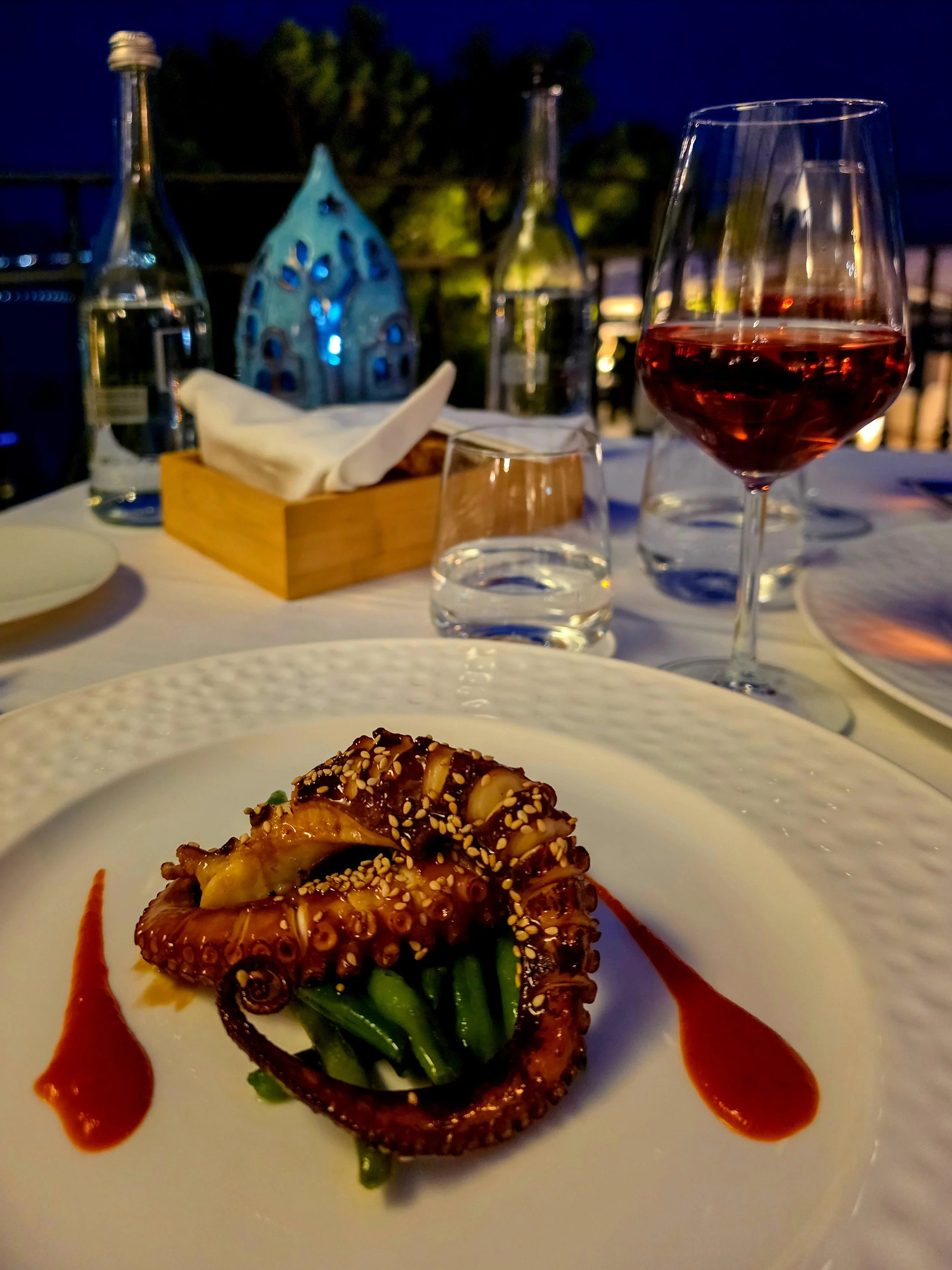 Grilled octopus dinner paired with rosé wine on an elegant evening terrace