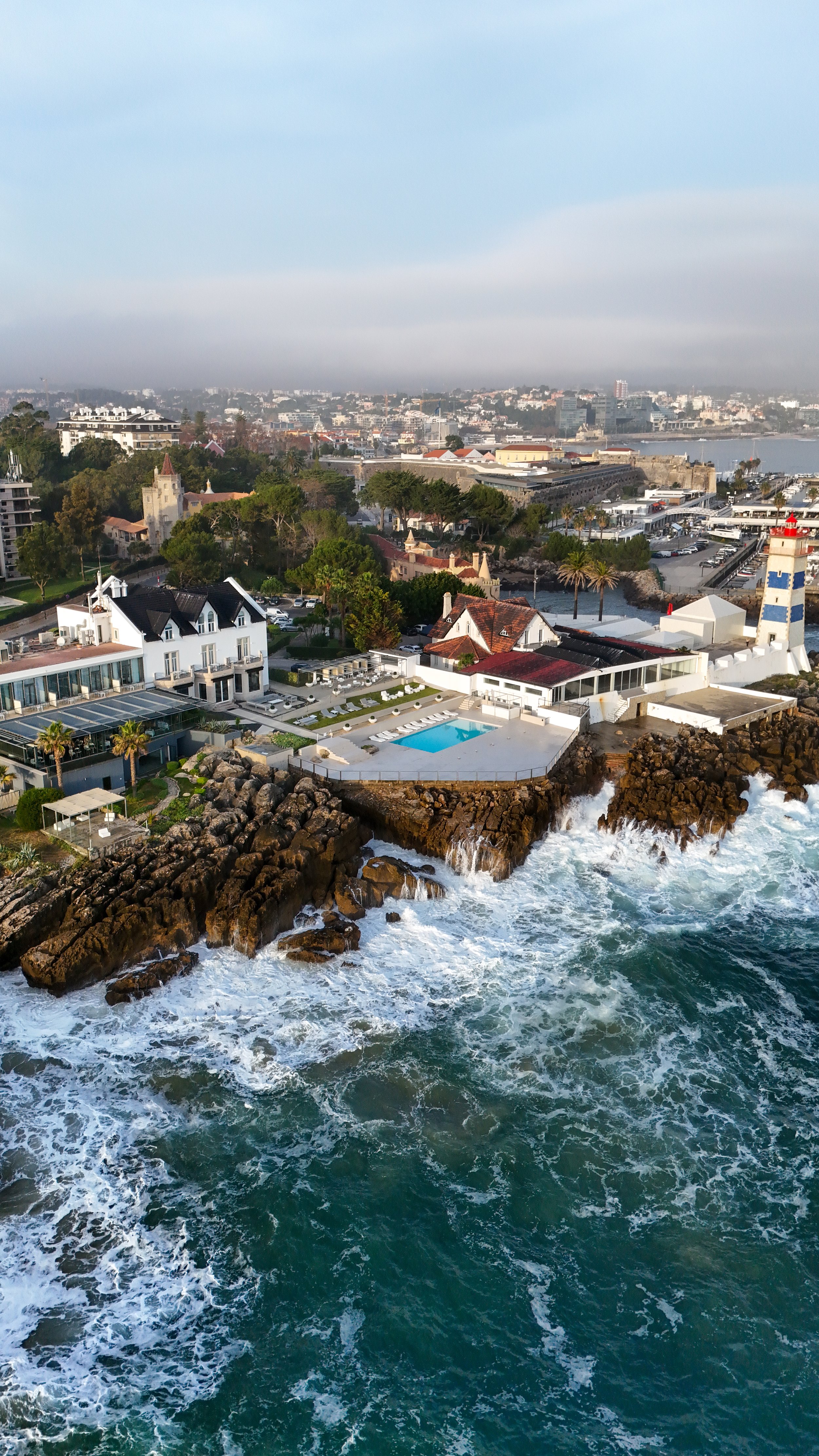 Drone perspective of Farol Hotel perched on the Atlantic shoreline beside Cascais Marina