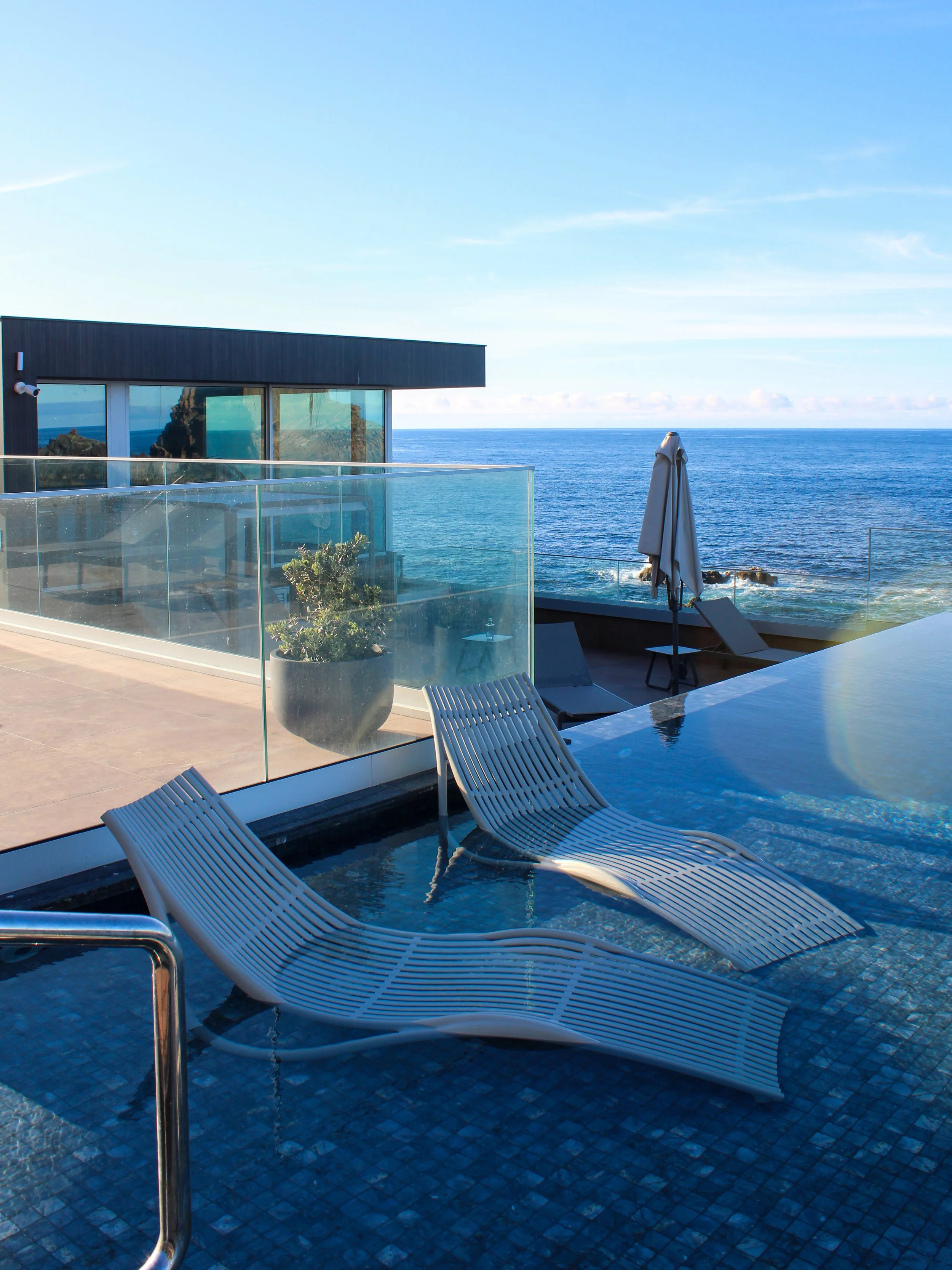 Rooftop infinity pool with submerged loungers overlooking the endless Atlantic Ocean