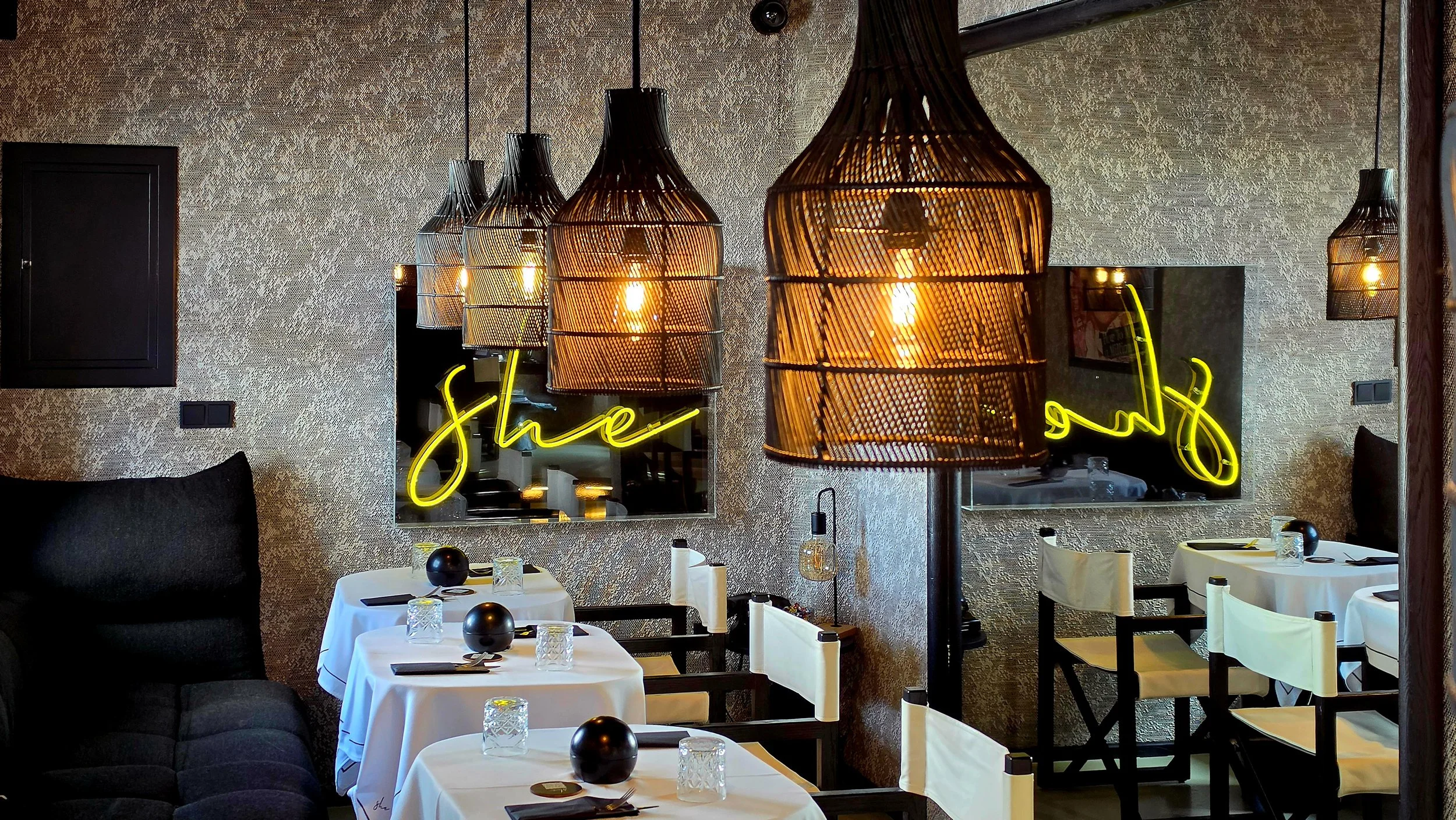 Elegant restaurant interior with woven pendant lights and neon details at She Mykonos Hotel in Mykonos, Greece