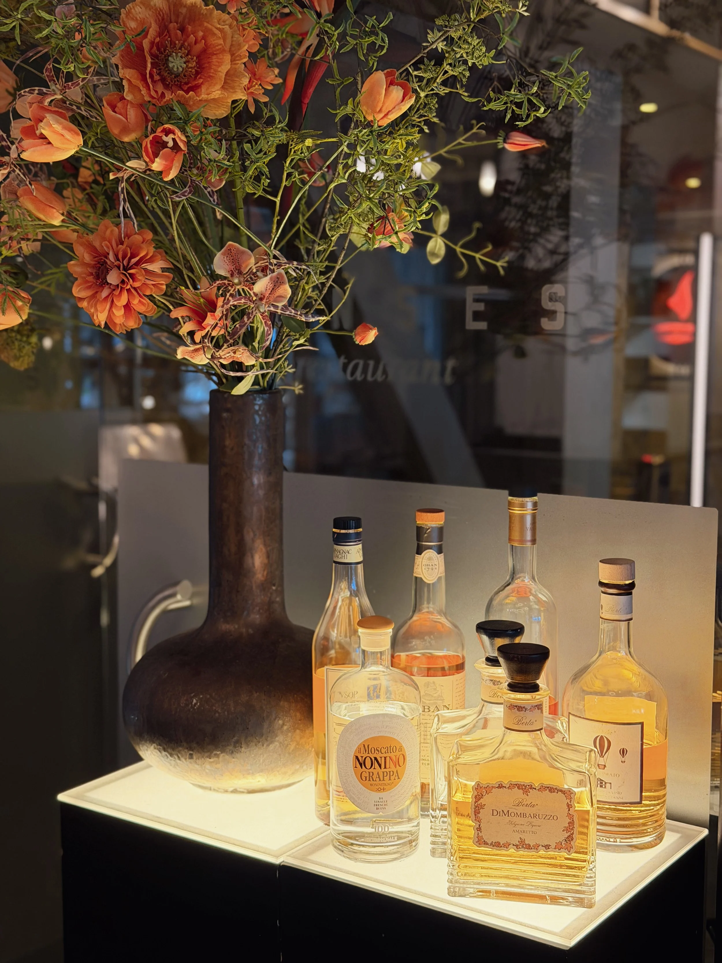 Elegant floral arrangement beside a curated selection of premium spirits