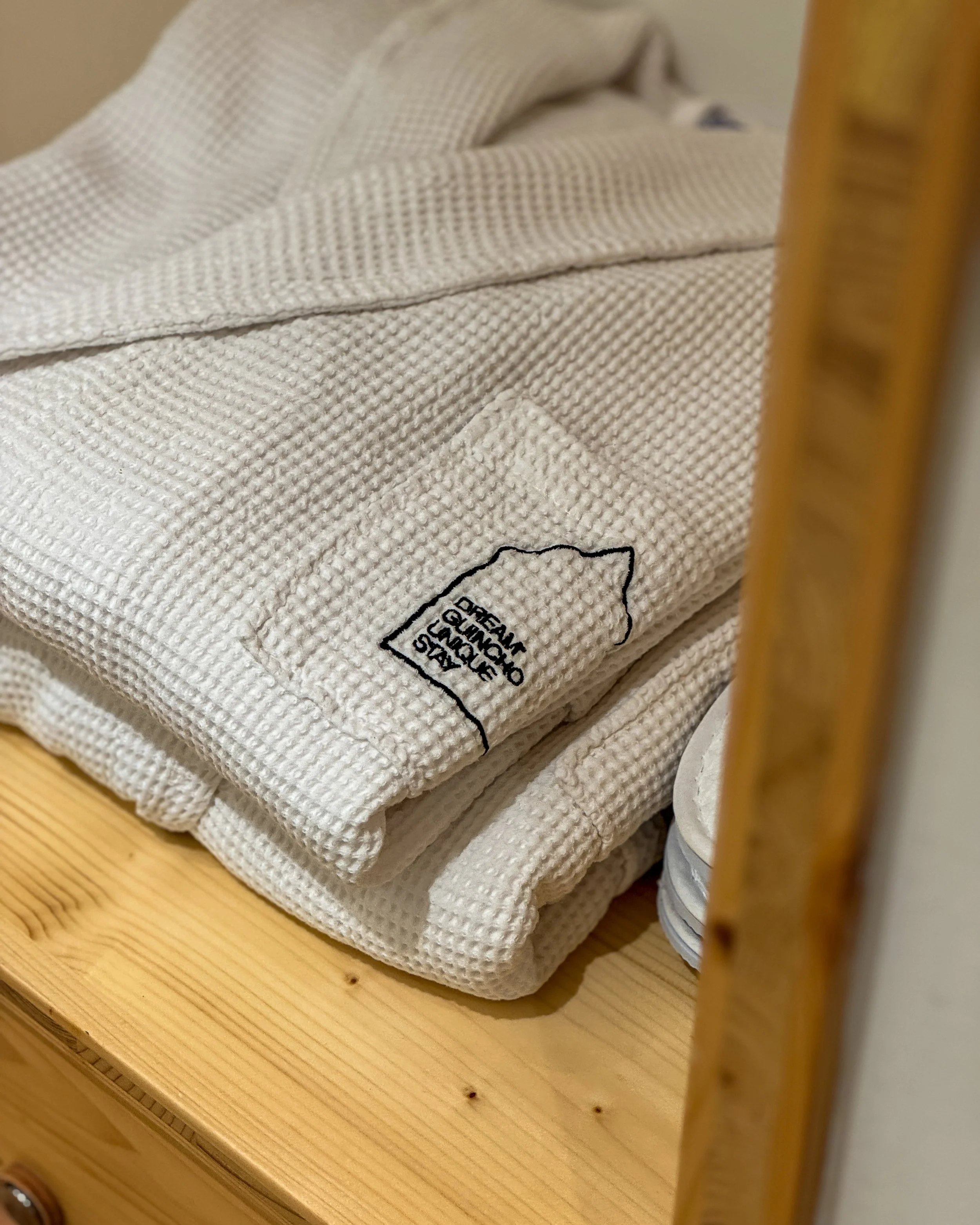 Soft waffle-textured robes neatly folded, reflecting the cozy and minimal aesthetic of Dream Guincho