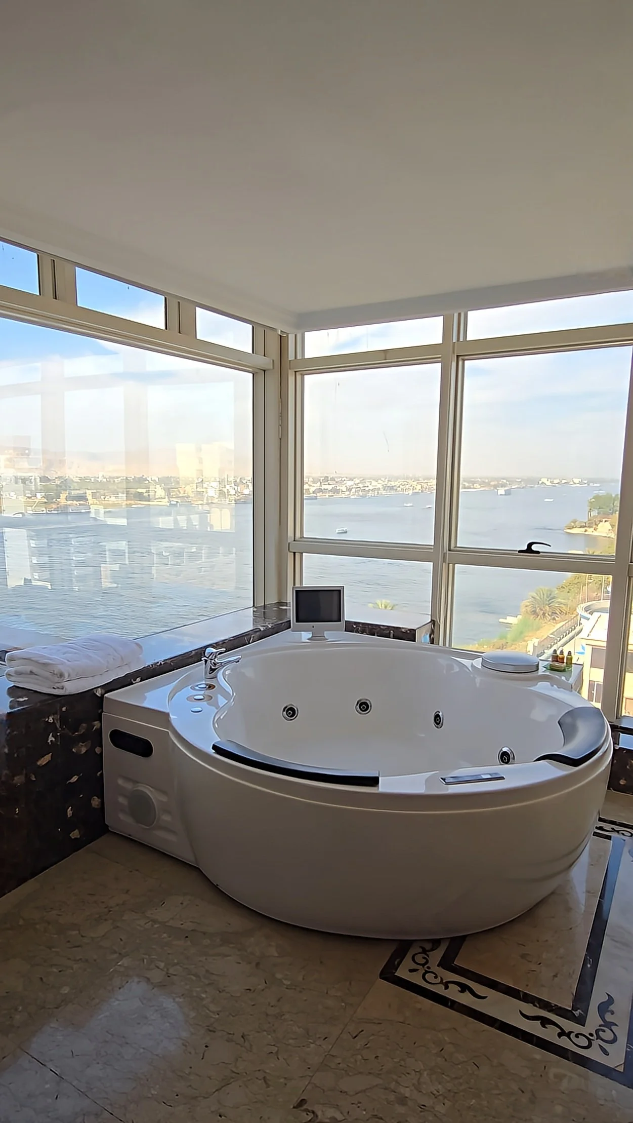 Jacuzzi bathtub positioned beside panoramic windows with sweeping views of the Nile River, Sonesta St. George Hotel Luxor.
