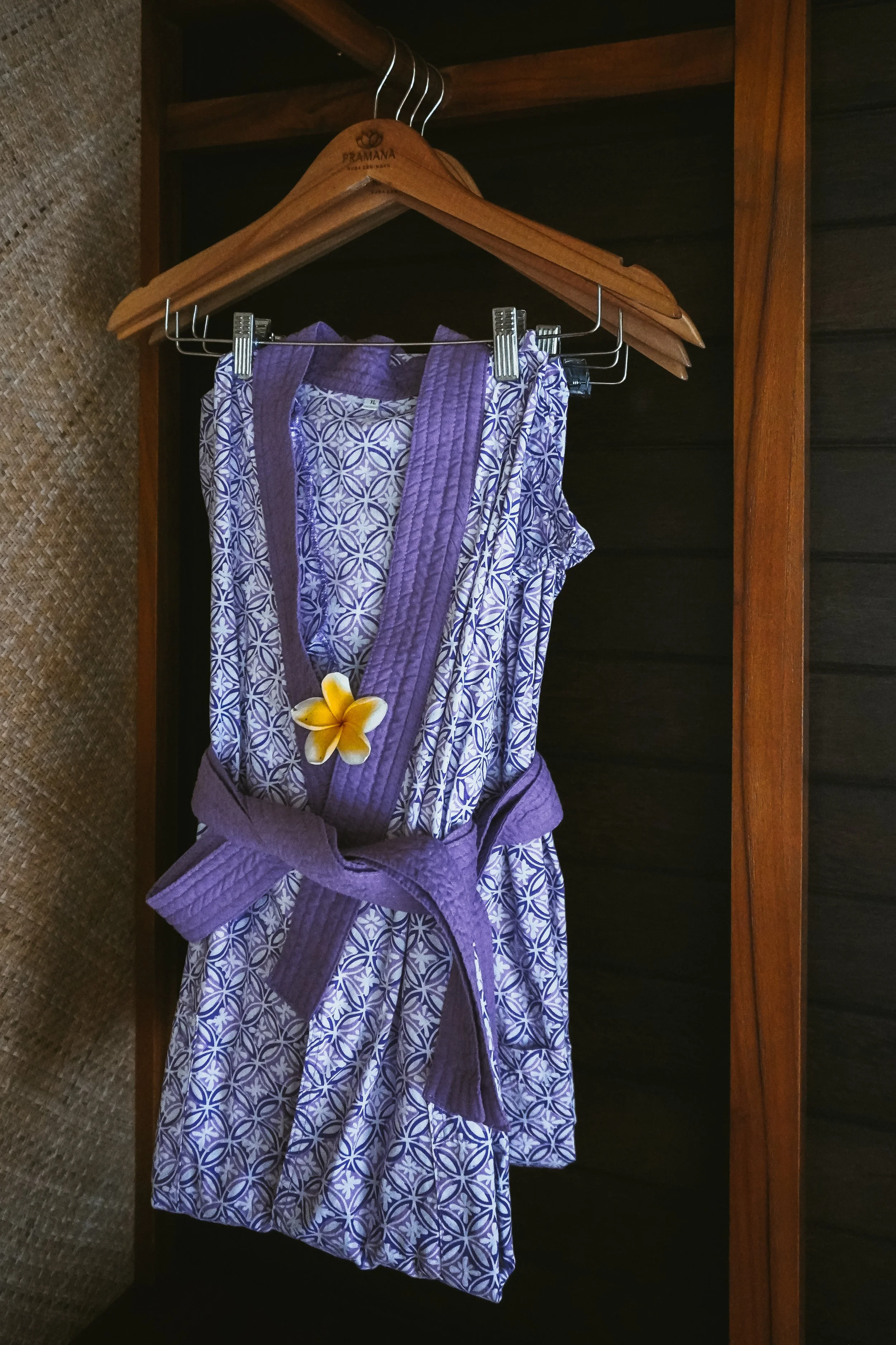 Patterned robe hanging in wooden wardrobe with tropical design details at Pramana Nusa Ceningan Resort Bali