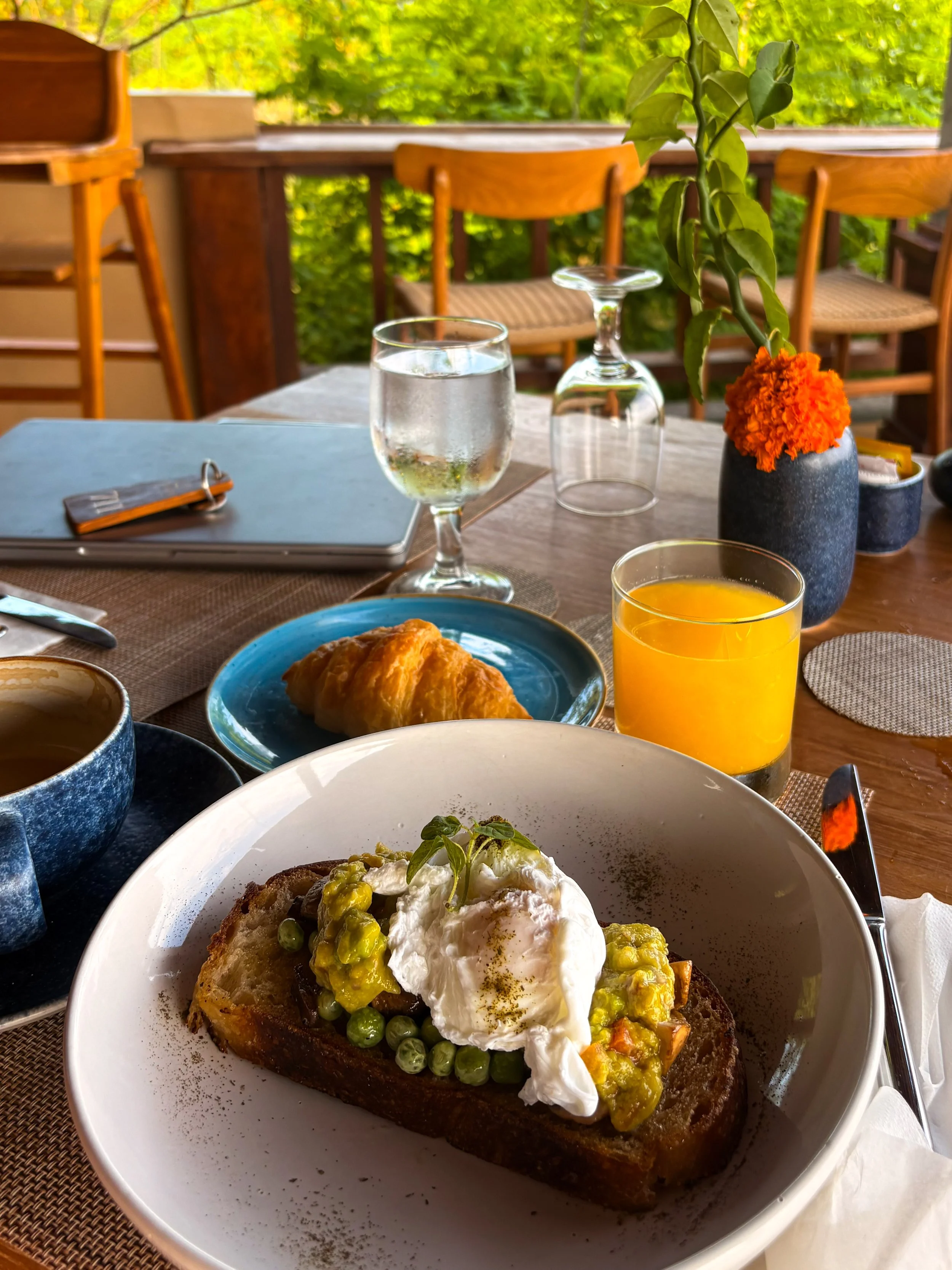 Breakfast with avocado toast, poached egg, croissant, and juice on terrace at Pramana Nusa Ceningan Resort Bali