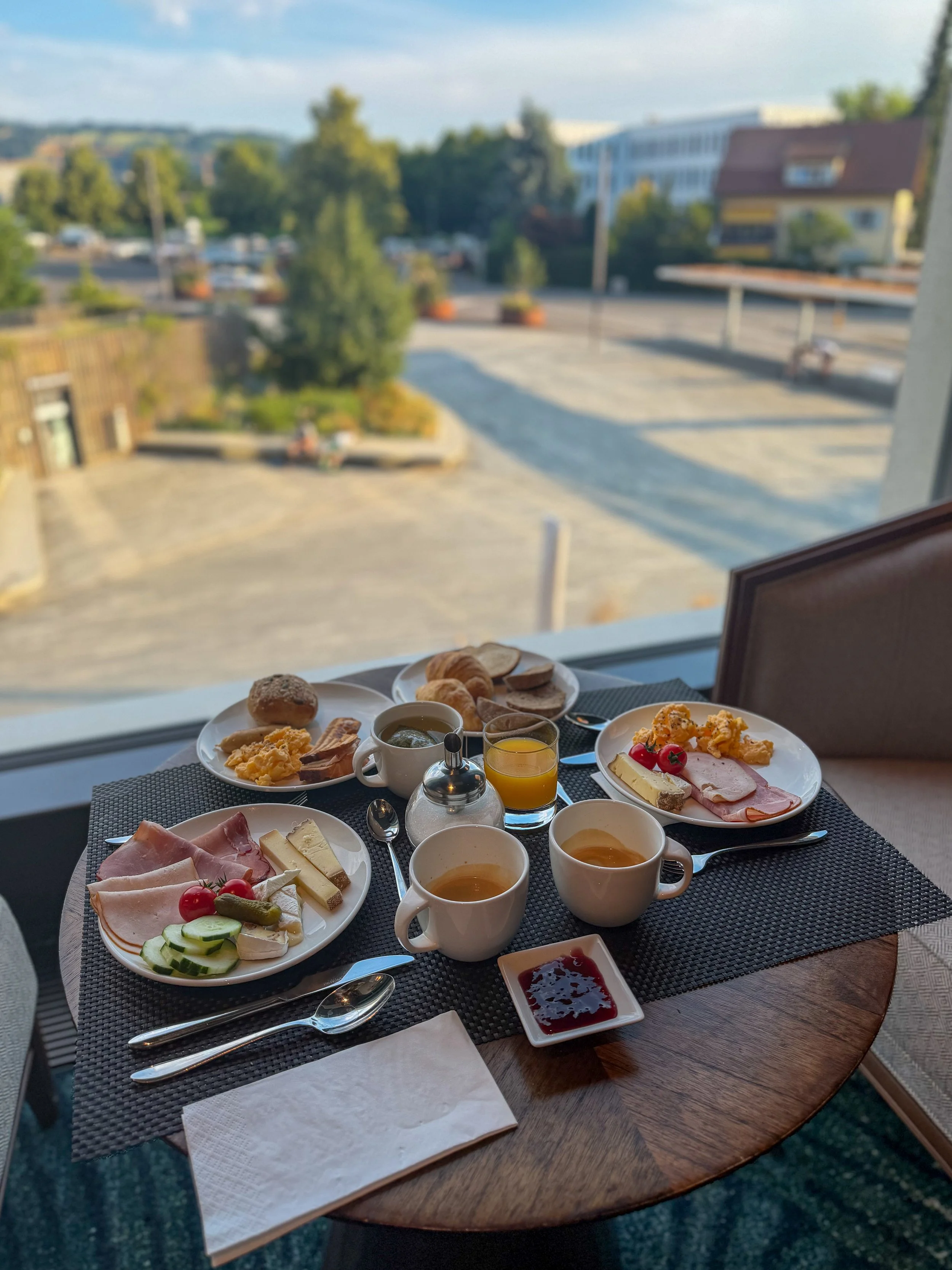 Breakfast spread with local cheeses, pastries, fresh fruit, and mountain views through large windows
