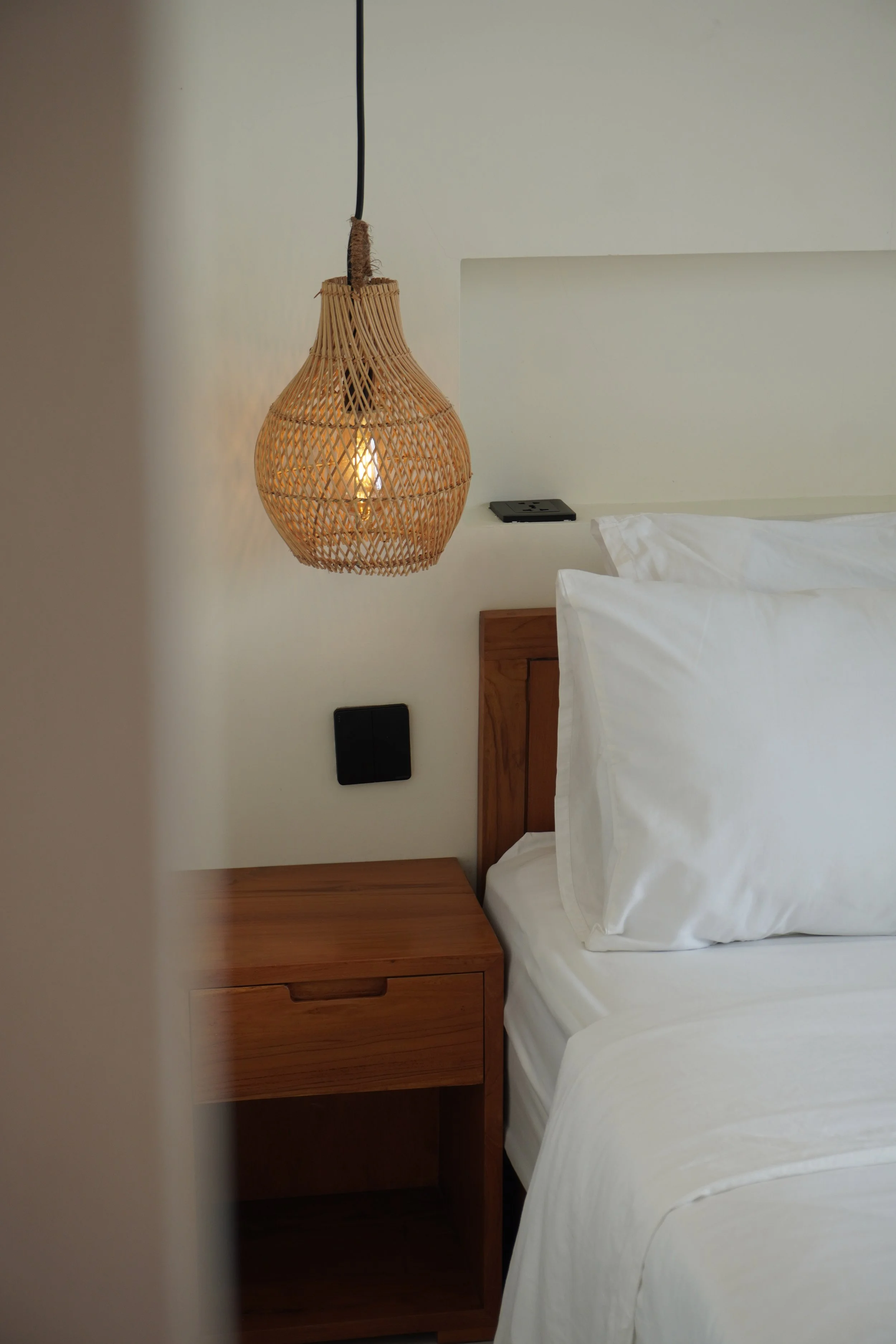 Cozy boutique guest room featuring warm wood accents and woven lighting