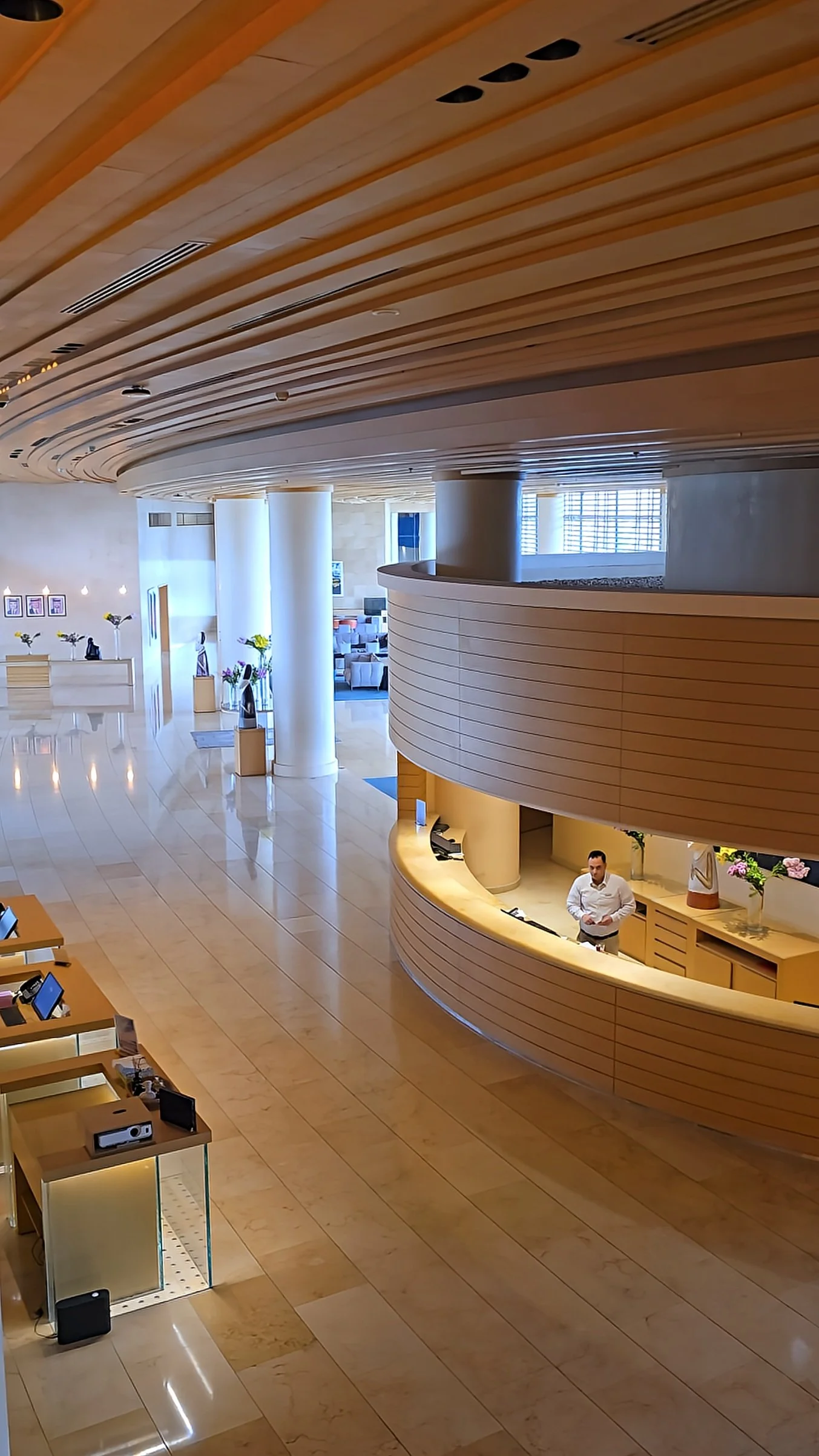 Grand lobby with curved wooden reception desk, high ceilings, and polished marble floors in a contemporary design, Kempinski Hotel Aqaba Red Sea – Aqaba, Jordan.