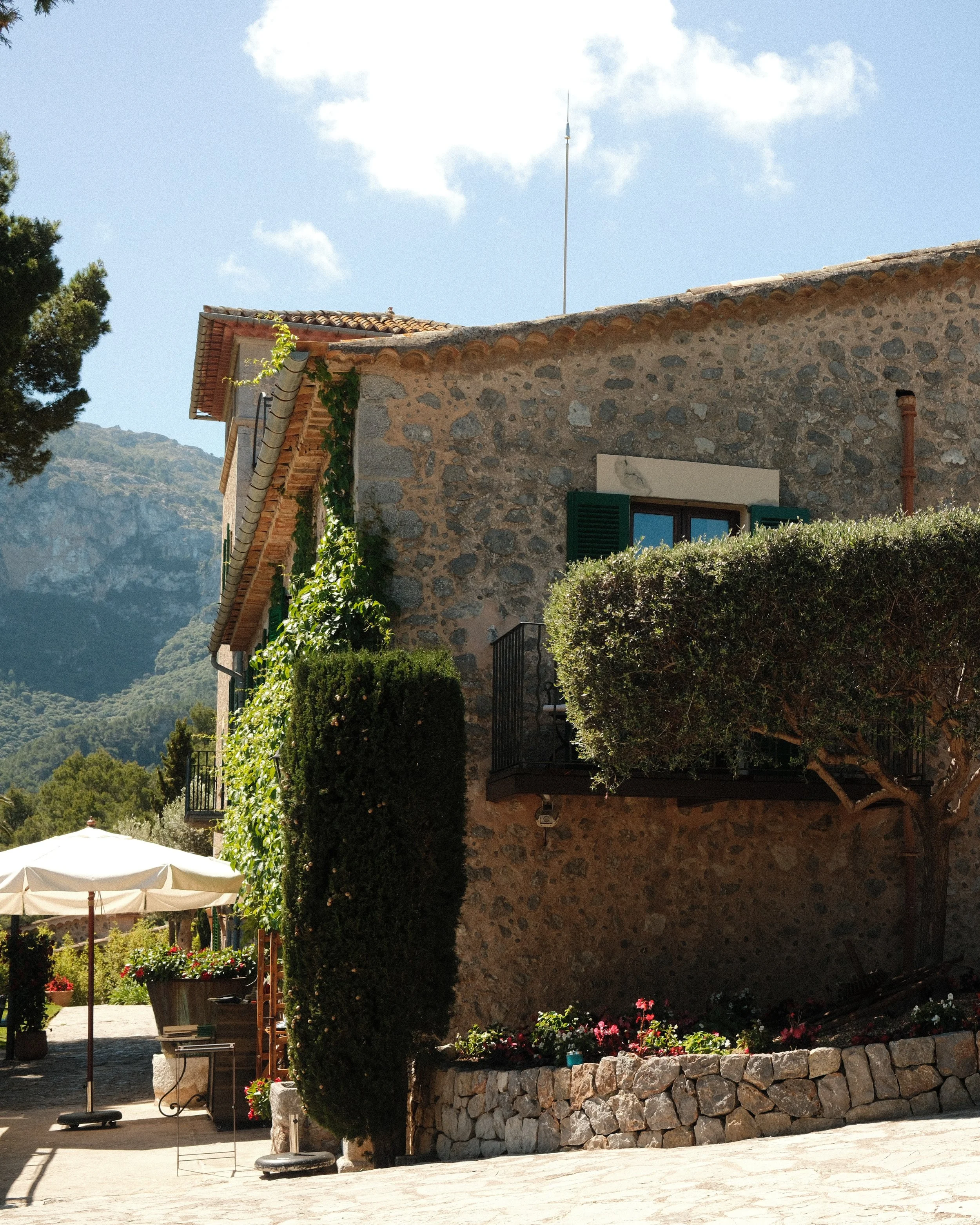 Historic stone façade covered in greenery with mountain views at Sa Pedrissa, a countryside retreat in Deià, Mallorca