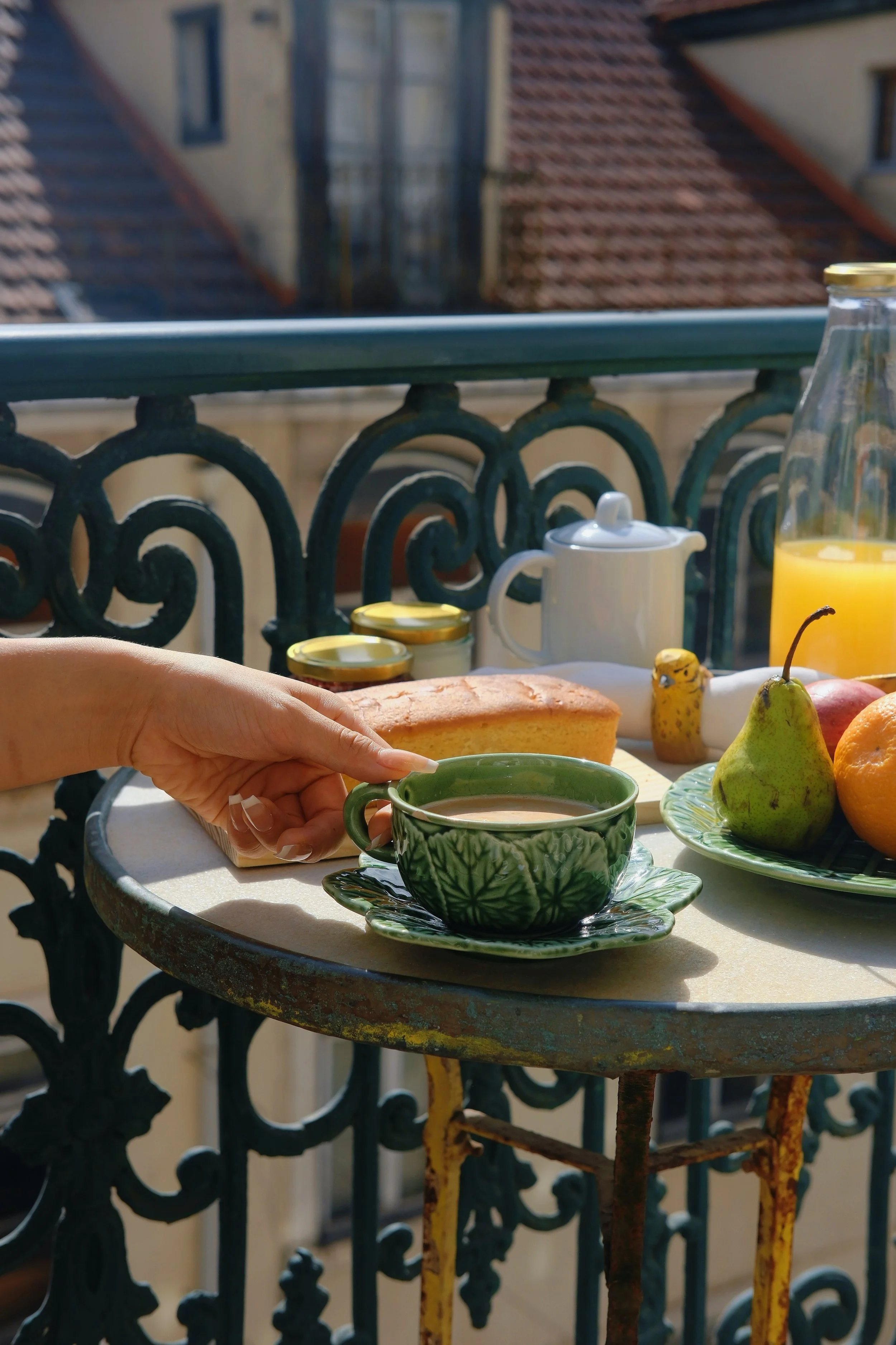 Breakfast with coffee, fresh fruit, and pastries served on a sunny balcony