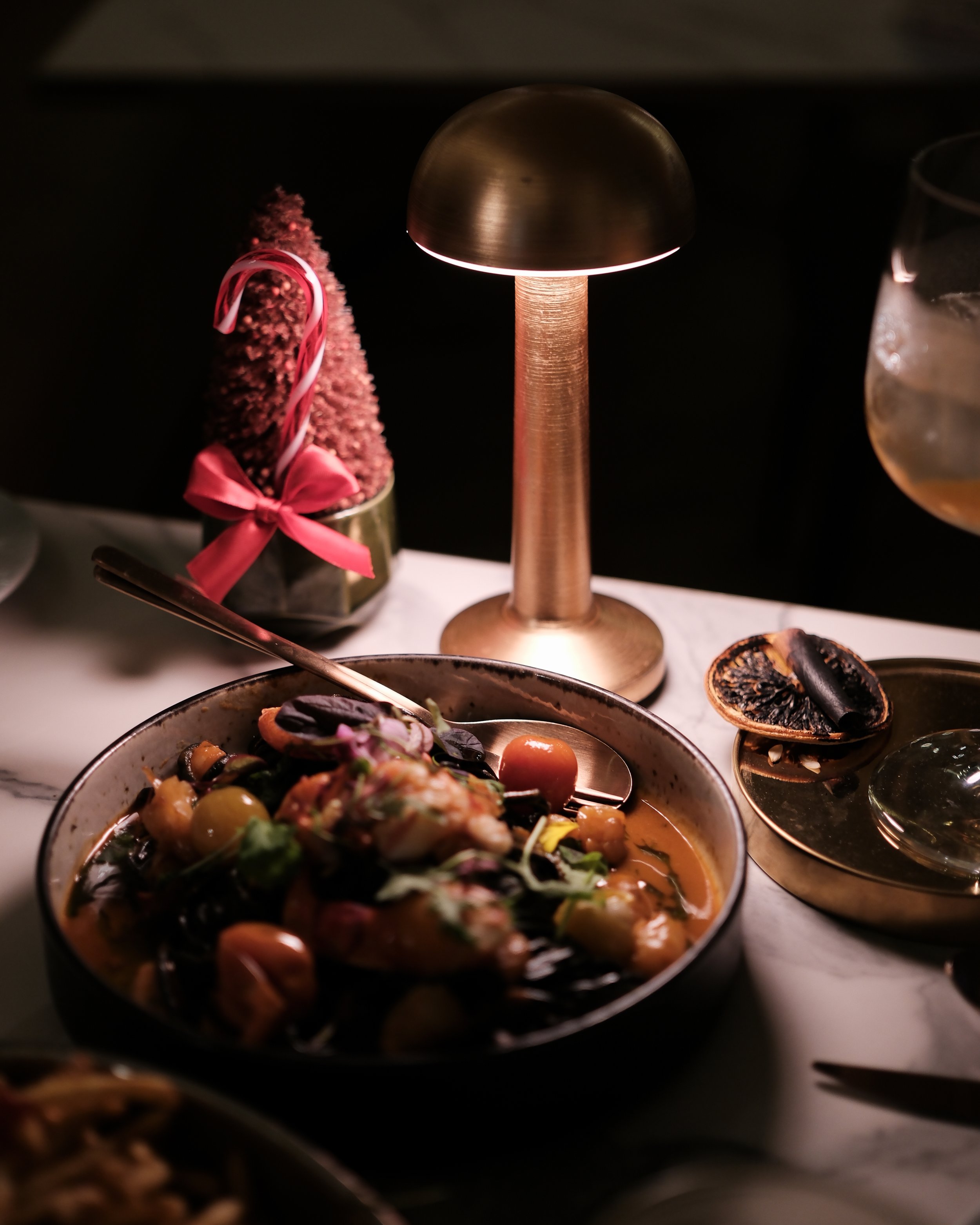 Warm, intimate dining scene featuring a seafood dish illuminated by a gold table lamp — Hyatt Regency Lisbon