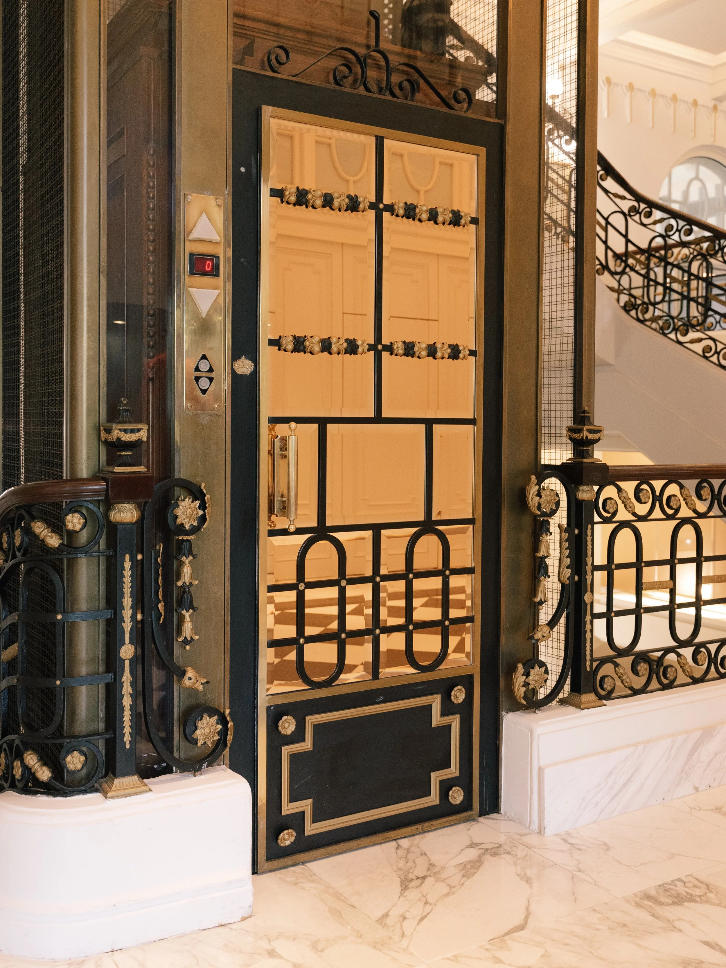 Restored vintage elevator with ornate ironwork and marble surroundings