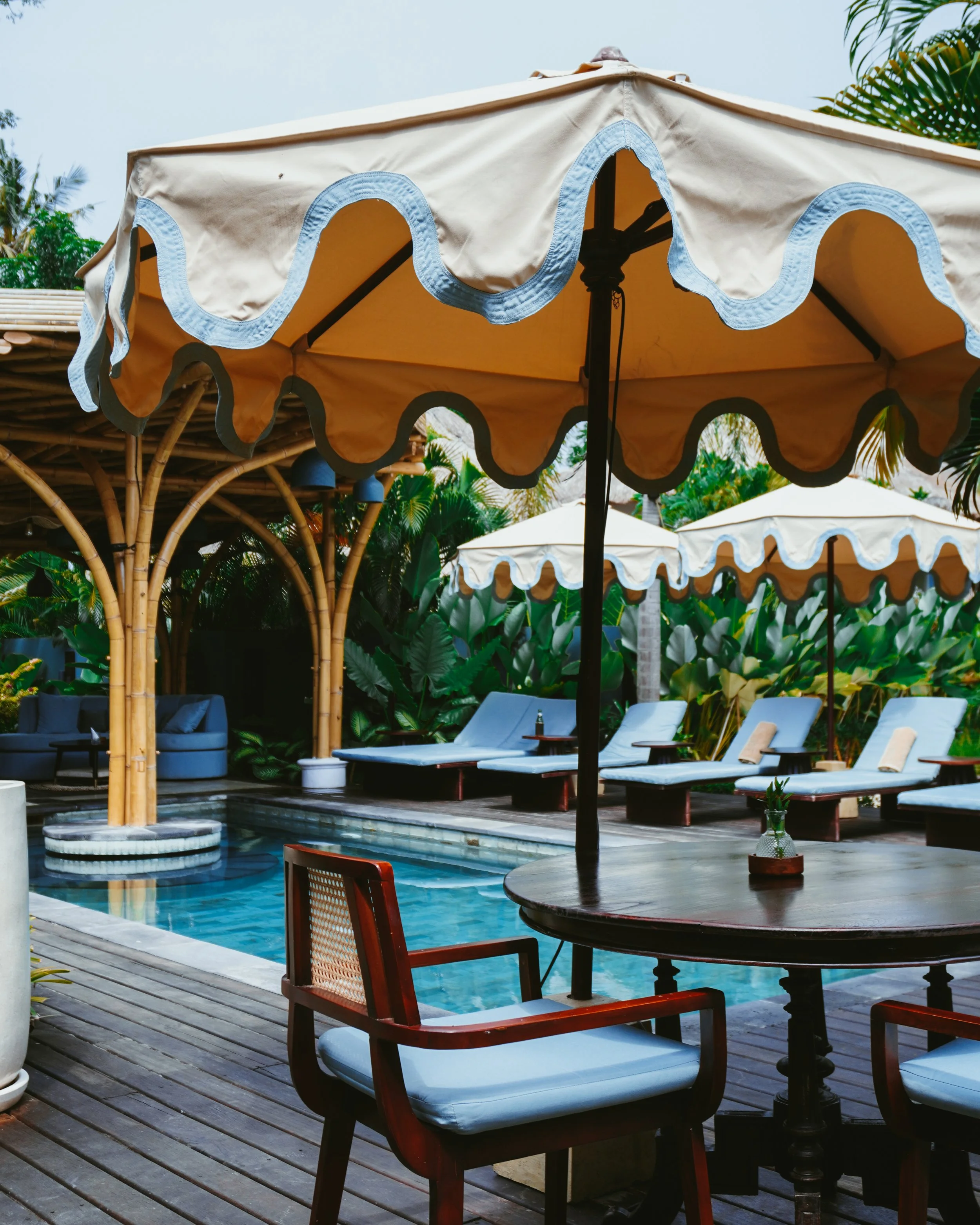 The swimming pool is framed by bamboo architecture and vibrant island greenery