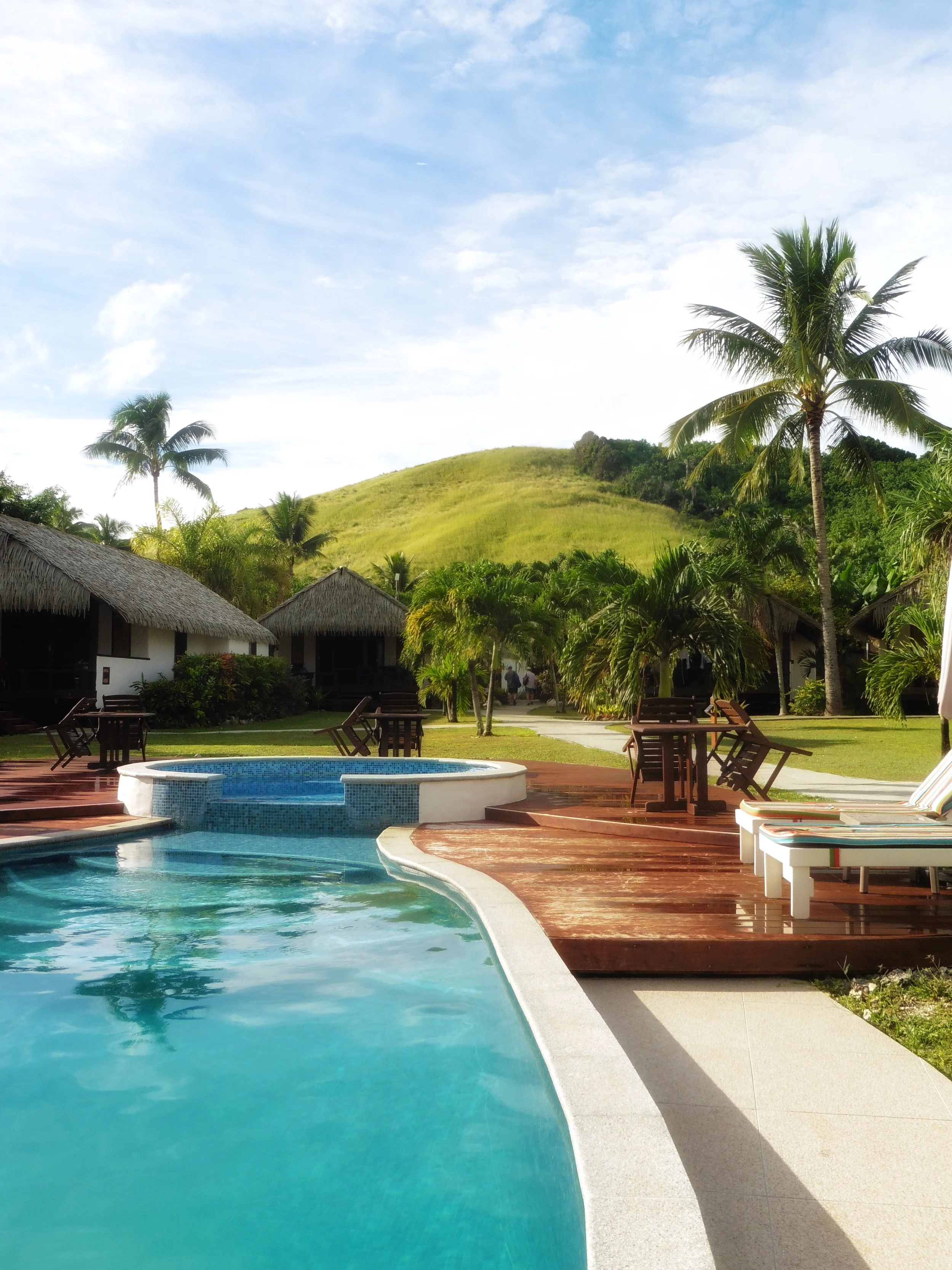 Resort pool with lush island hills in the background at Tamanu Beach Resort, Aitutaki