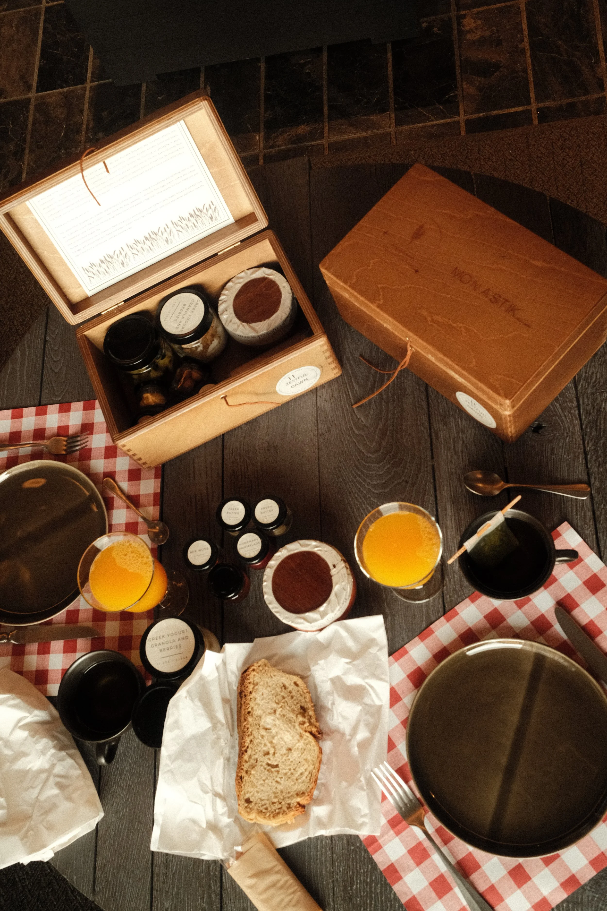 Curated breakfast spread with artisan bread, yogurt, preserves, orange juice, and reusable wooden boxes