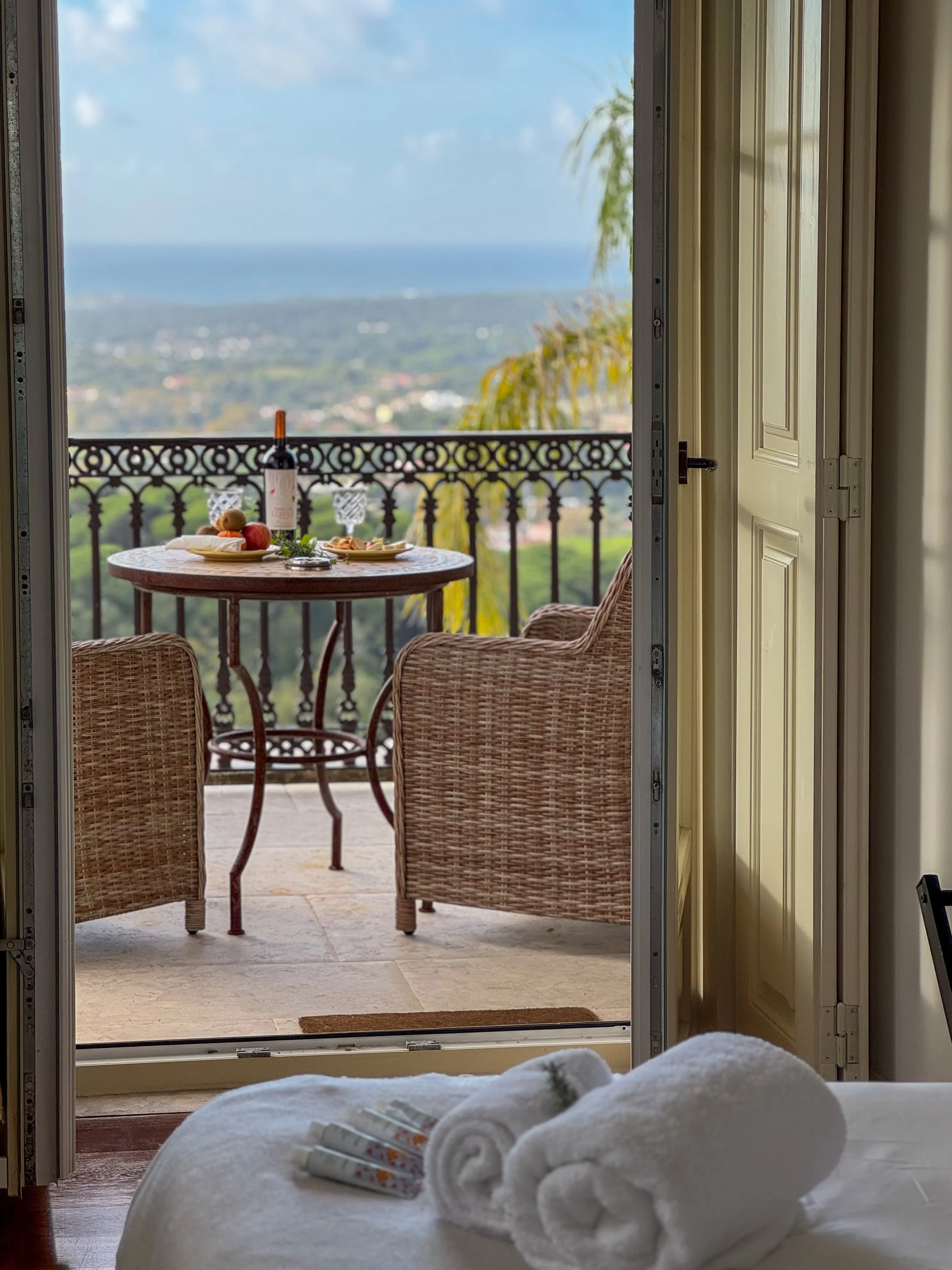 A private balcony set for wine and fruit opens to sweeping Atlantic and Sintra views