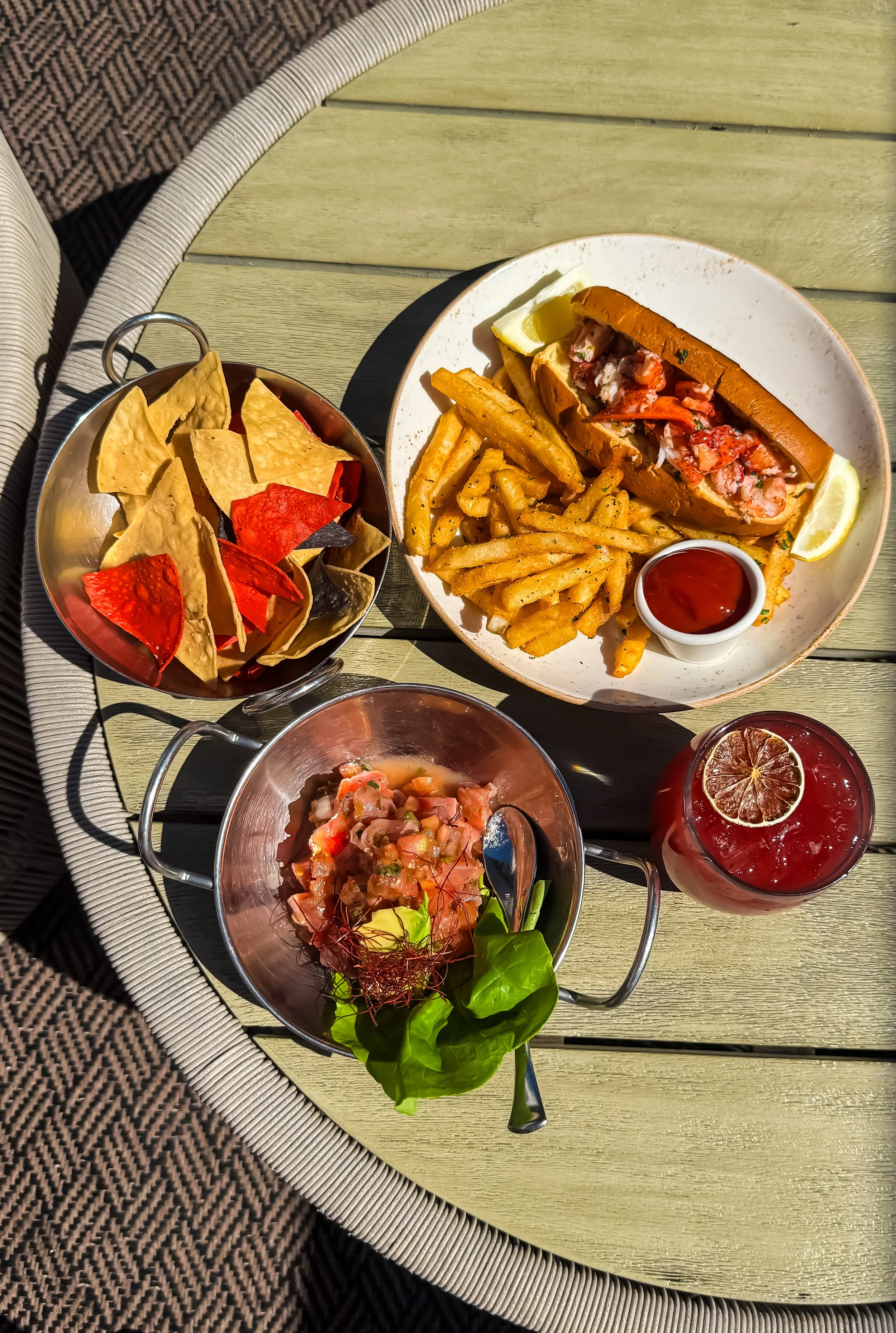 Poolside dining with lobster roll, fries, chips, and cocktails served on a sunlit rooftop table, Andaz San Diego – San Diego, California.