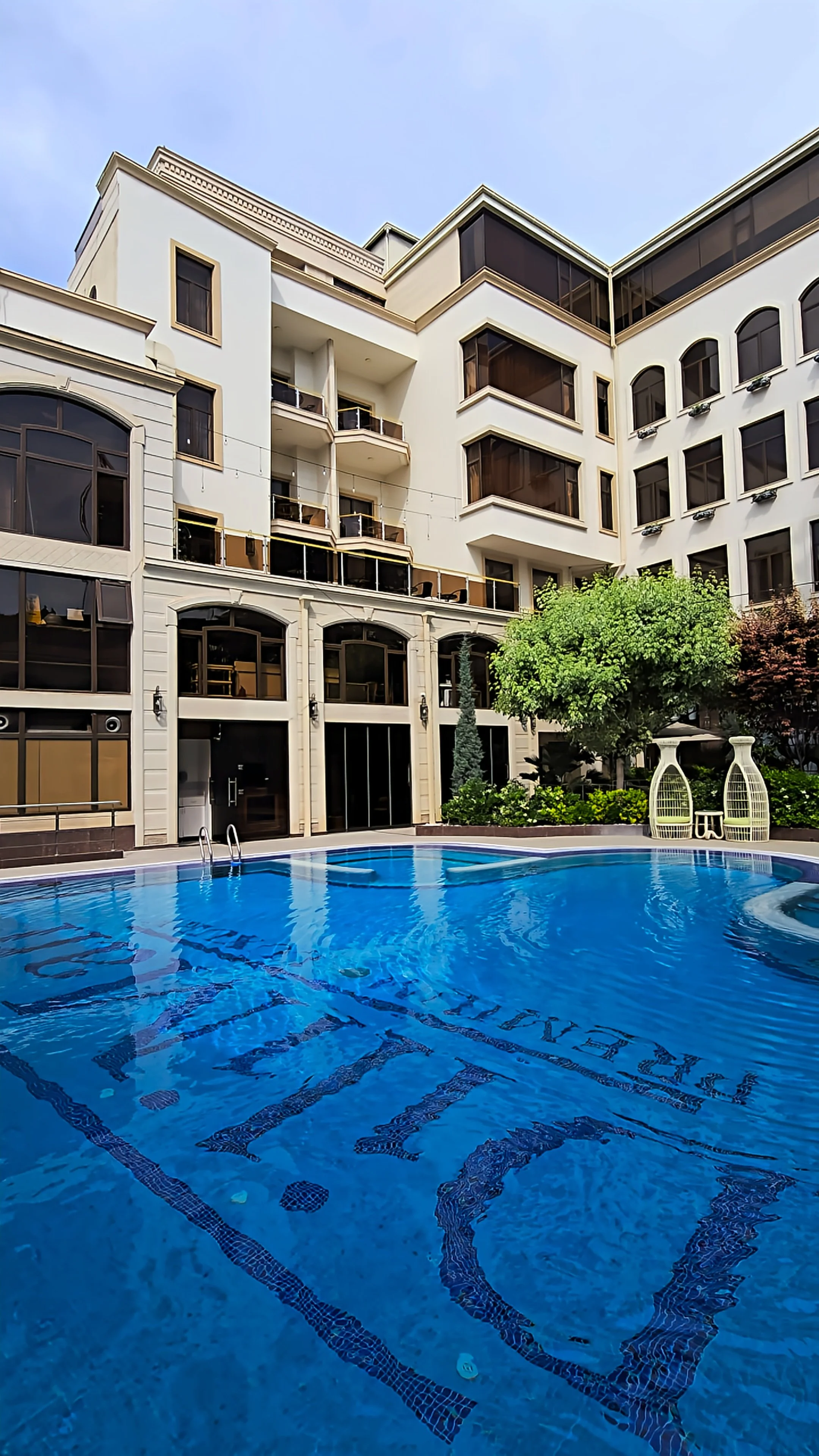 Courtyard swimming pool framed by classic architecture and landscaped gardens at Dilimah Premium Luxury Hotel